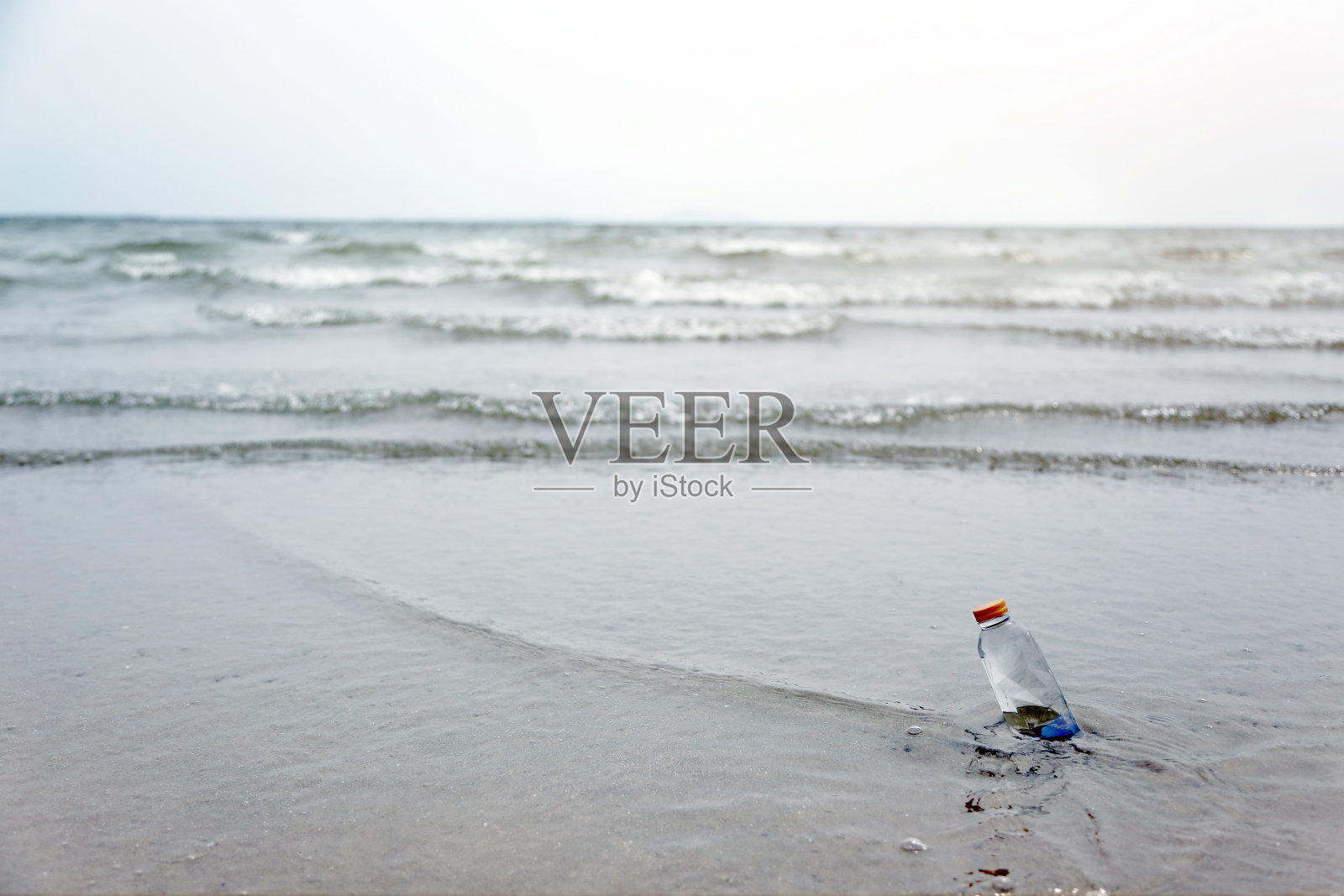 在海洋沙滩上，瓶子里装着淡水照片摄影图片