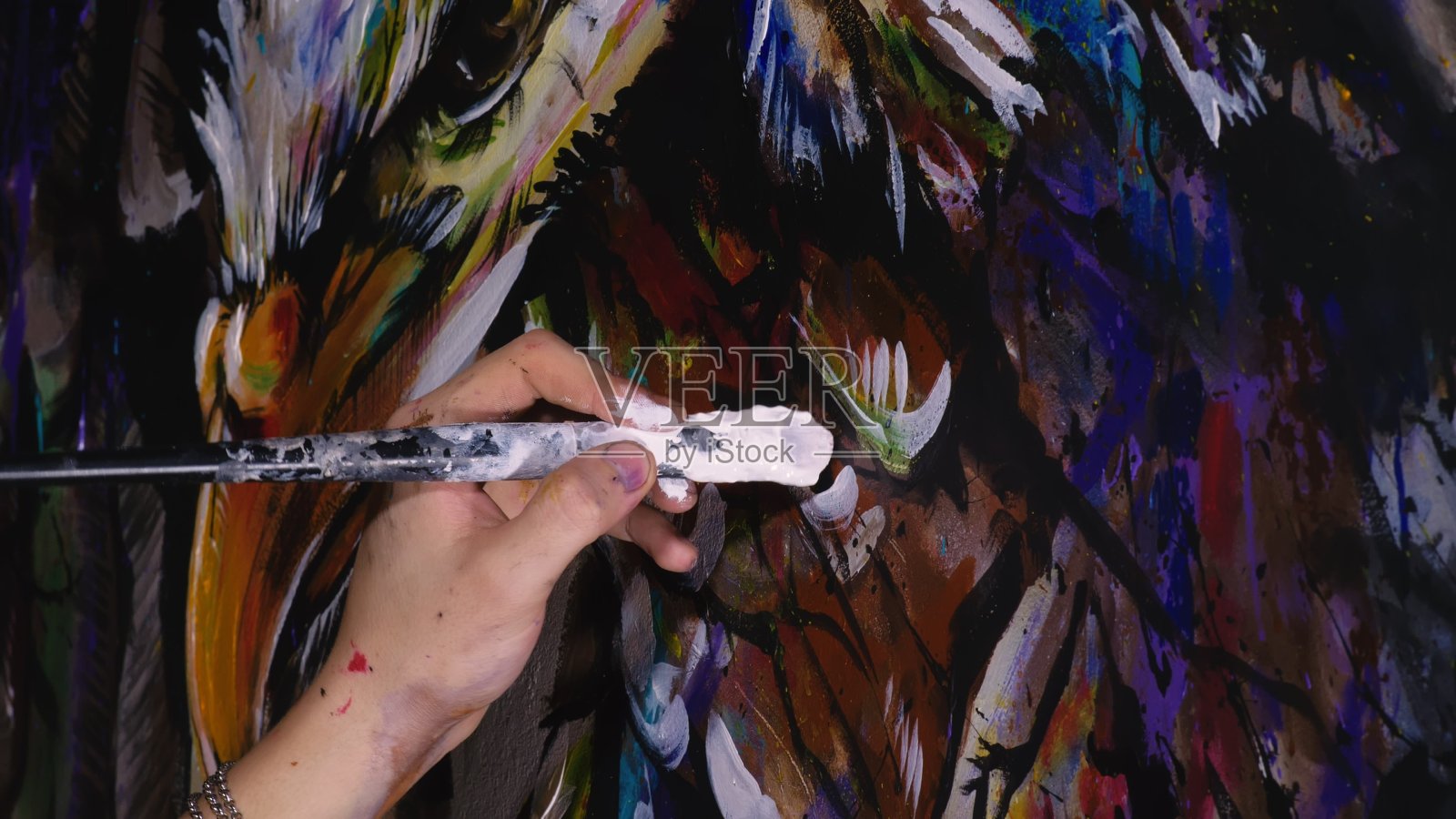 艺术家设计师在墙上画了一只鹰。工匠装饰用丙烯酸油彩刷画一幅画。近距离的黑暗魔法电影外观。插画图片素材