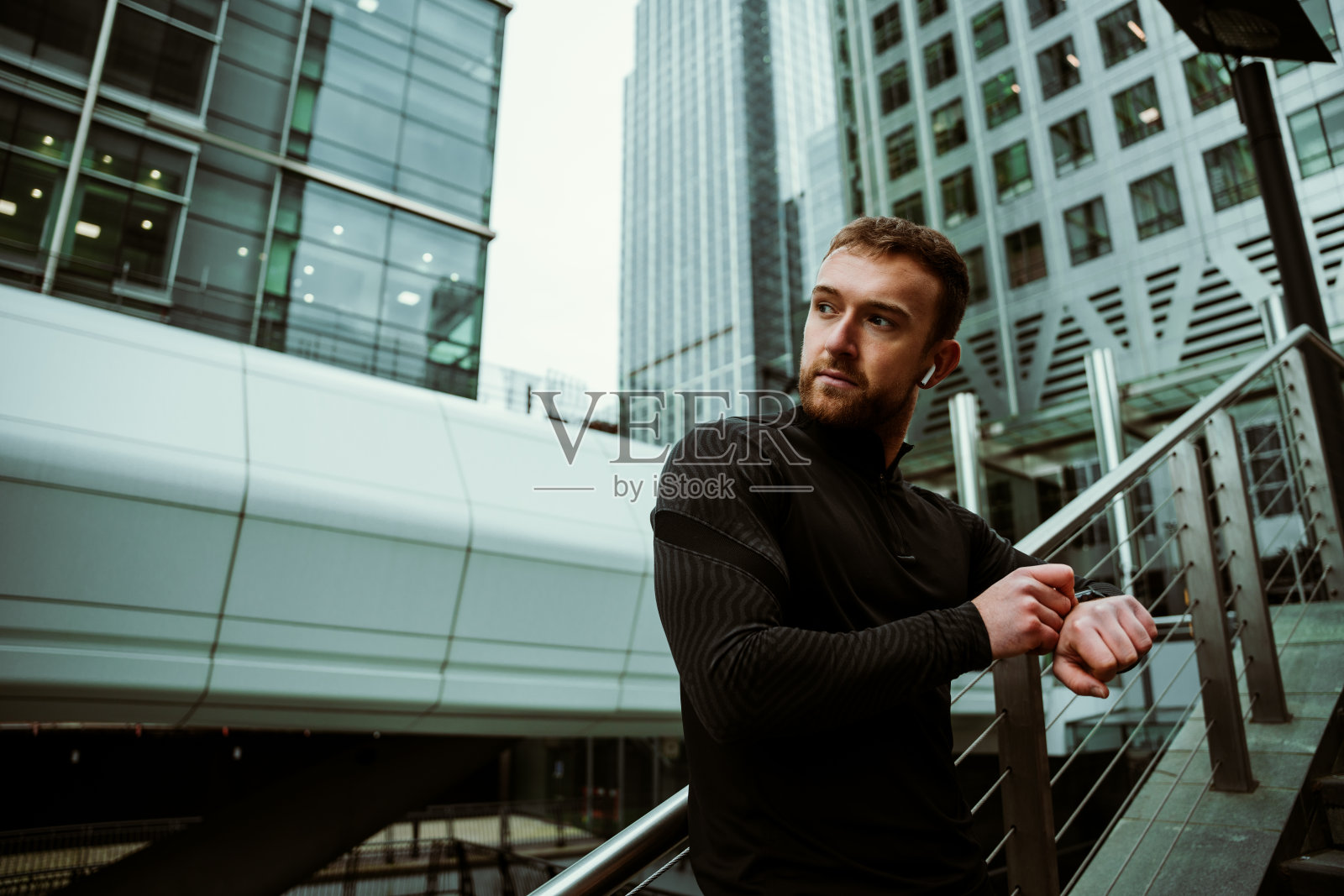 白人男性运动员听音乐耳机调整手表准备跑步照片摄影图片