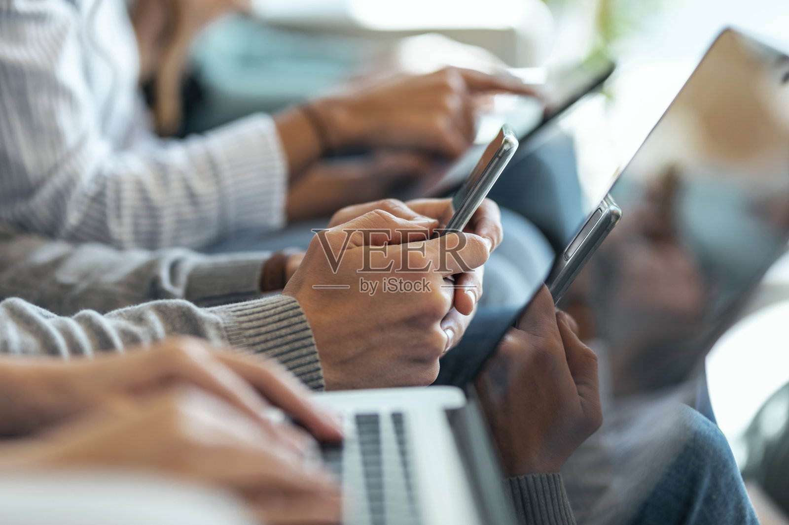 优雅的商务人士用她的笔记本电脑和智能手机一起坐在沙发上共同工作。照片摄影图片