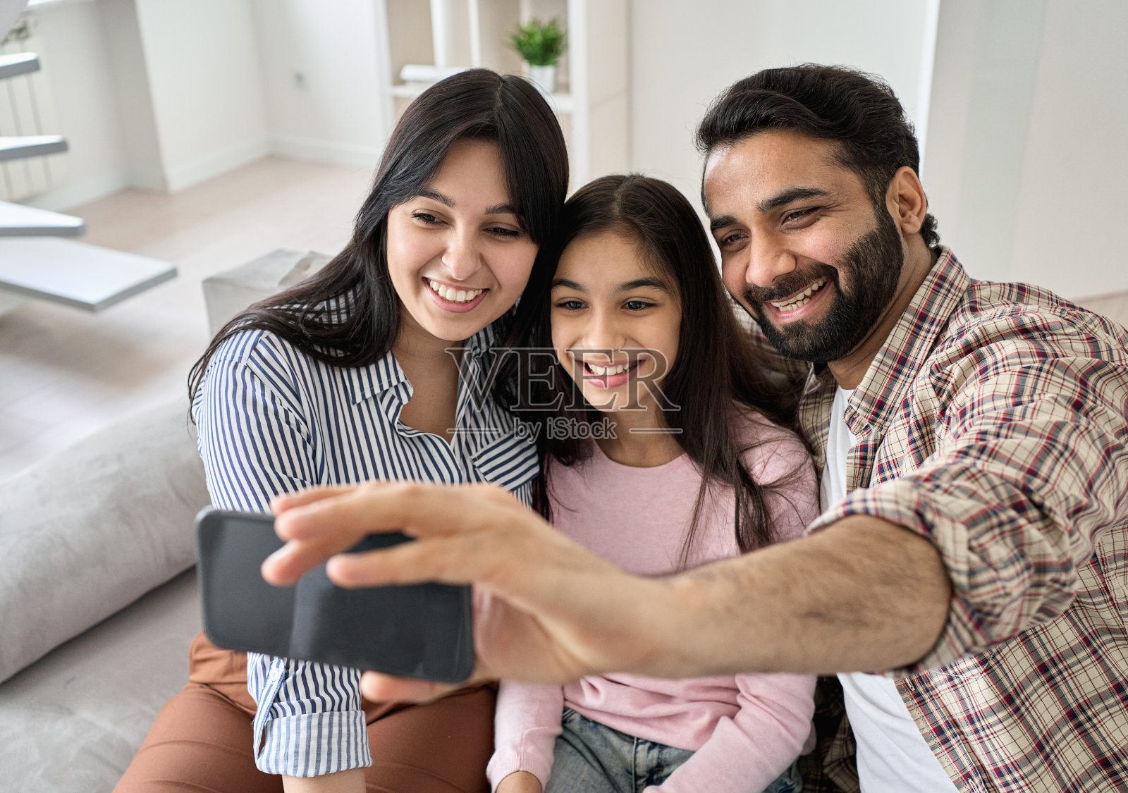 快乐的印度家庭用智能手机进行虚拟通话照片摄影图片