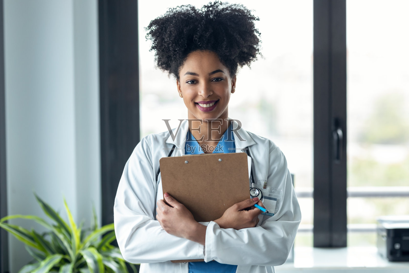非洲女医生拿着剪贴板，看着镜头站在会诊。照片摄影图片