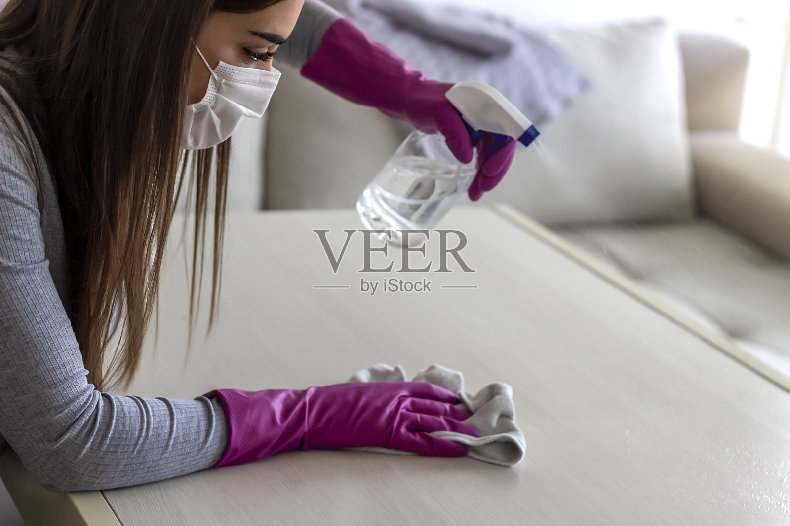 在家里用喷雾清洁剂清洁和抛光桌子的妇女。照片摄影图片