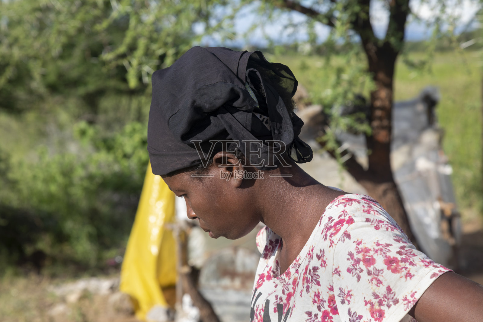 年轻的非洲妇女走在她村庄小屋前的院子里照片摄影图片