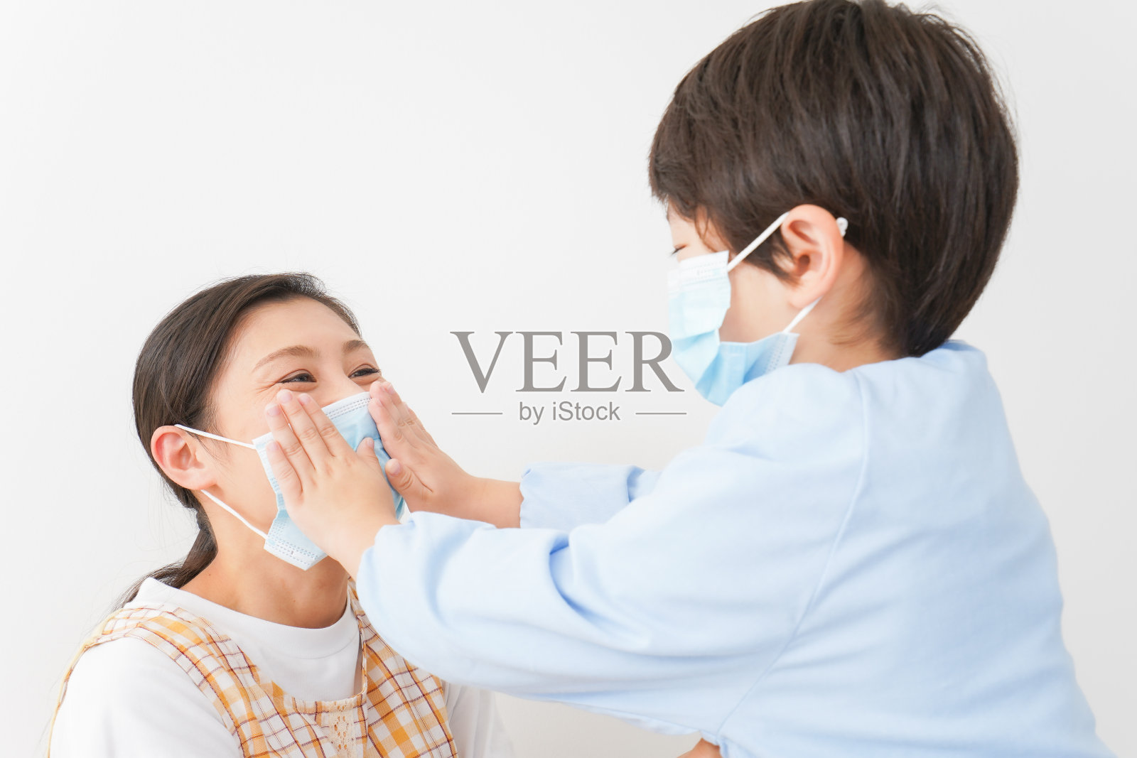 一个给母亲戴上面具的孩子。照片摄影图片