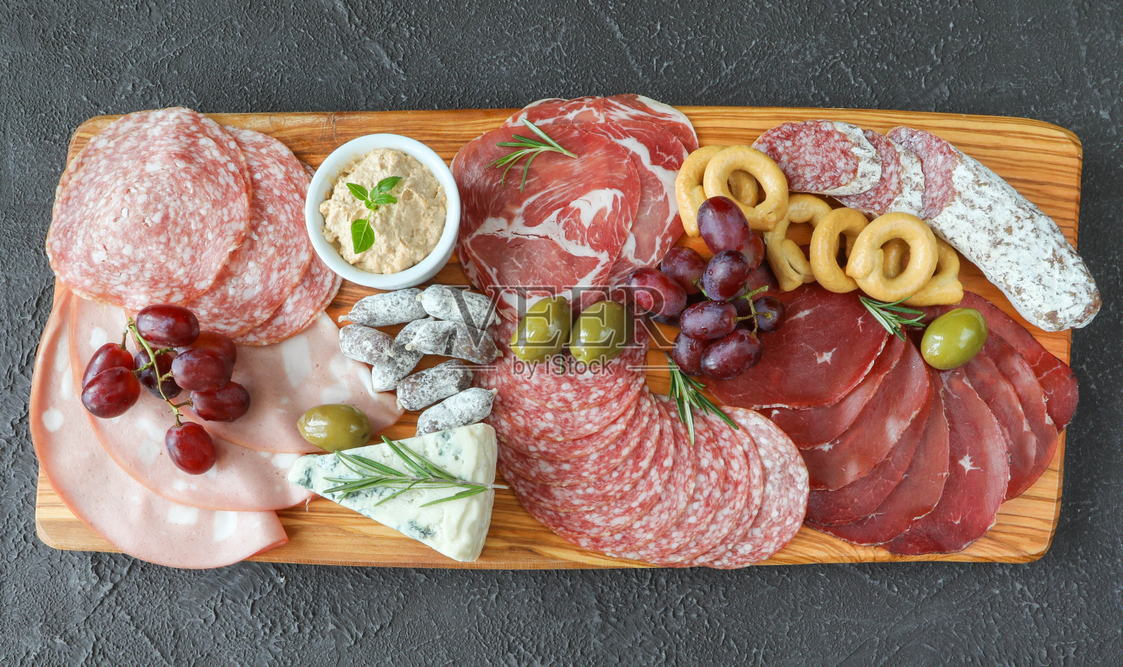 肉和奶酪板从意大利产品-熏火腿，摩泰台拉，费利诺，牛肉饼，戈尔根佐拉干酪，帕尔马干酪，肉酱，绿橄榄和迷迭香照片摄影图片