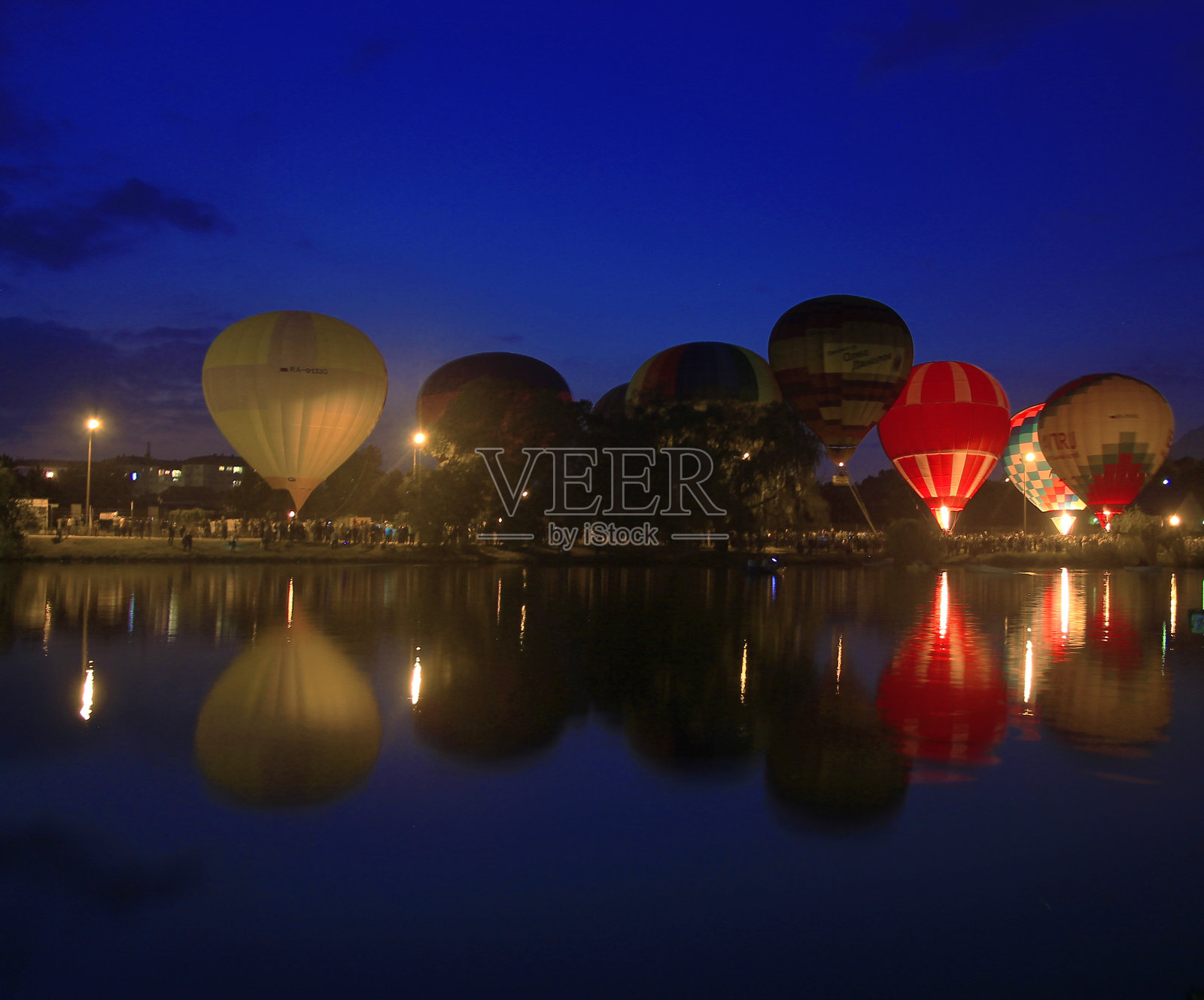 傍晚，热气球在湖边的天空中飞翔照片摄影图片