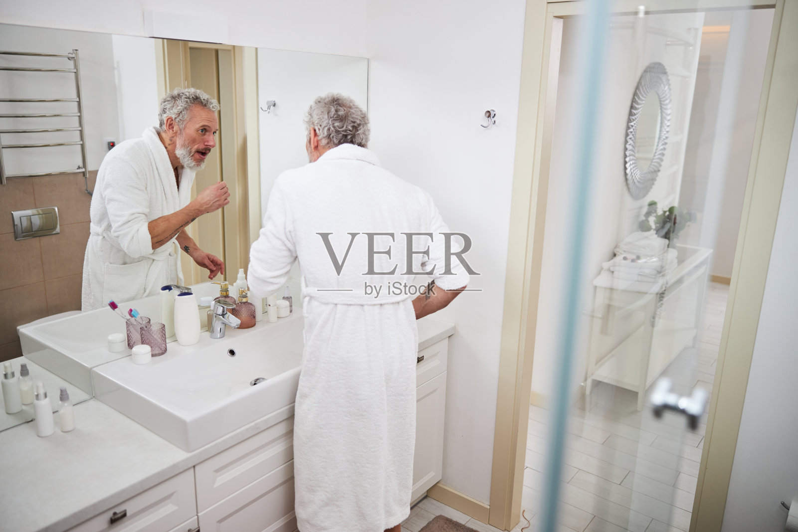 快乐自信的男士在现代室内房间的镜子中看倒影照片摄影图片