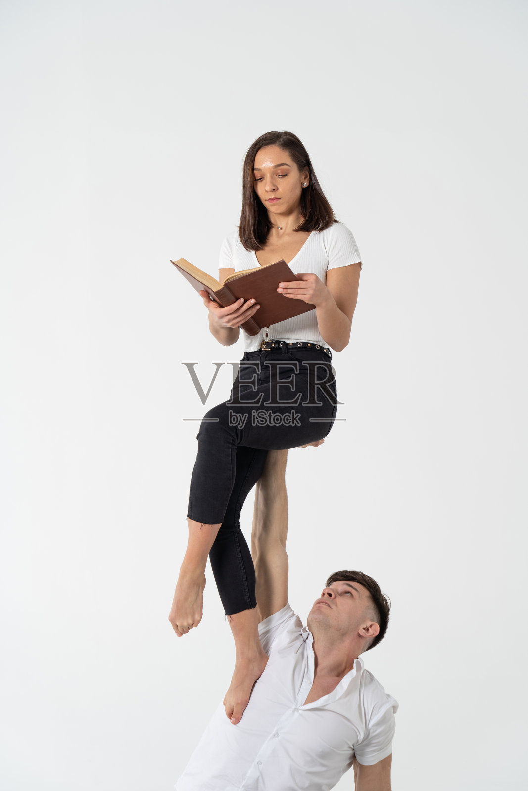 女子坐在男子手上看书的创意构图。支持、关怀、教育理念照片摄影图片