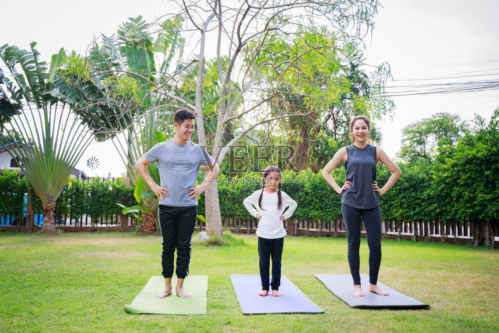 适合快乐的人在户外工作。亚洲家庭的父母和孩子的女儿一起在家庭花园的瑜伽垫上锻炼照片摄影图片