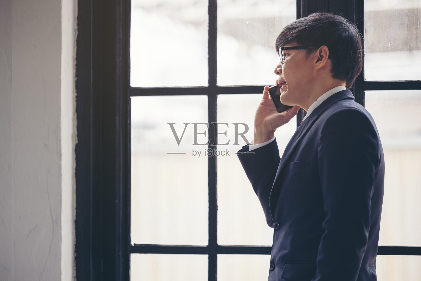 帅气的商人在阁楼室内工作室靠窗边打电话查看电子邮件照片摄影图片