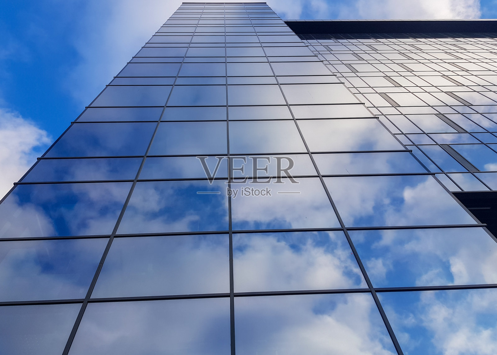 现代玻璃摩天大楼的观点。在玻璃摩天大楼中反射的多云的蓝色天空照片摄影图片