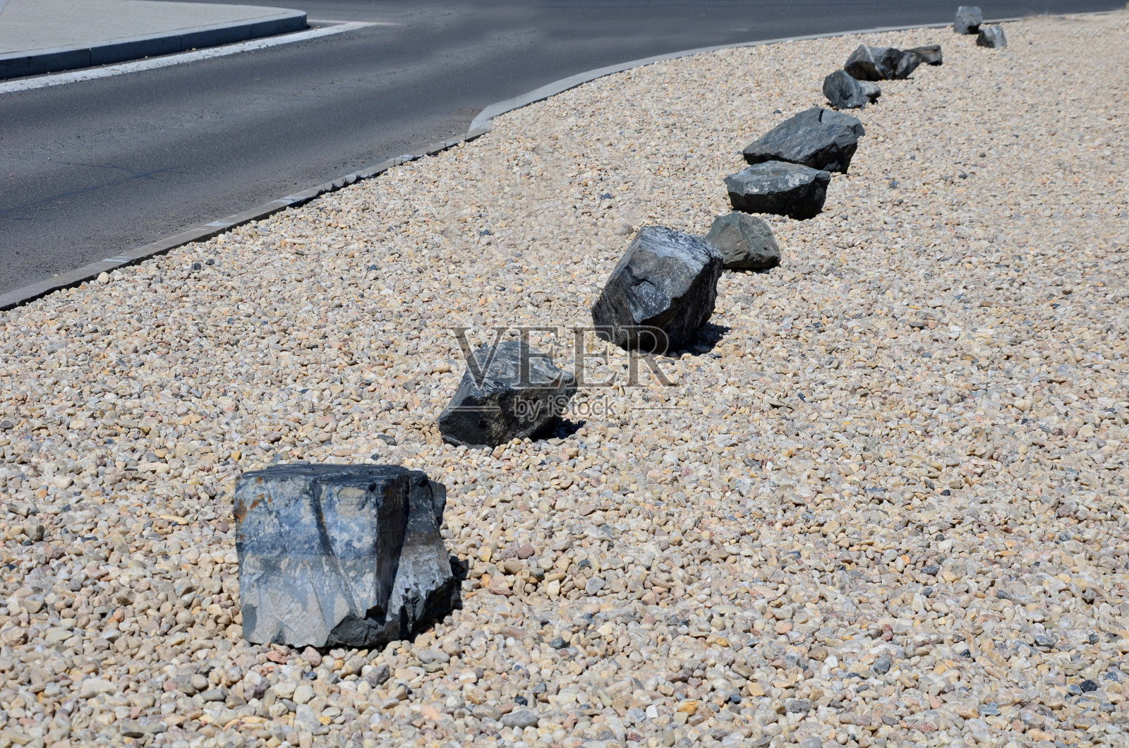 在小路之间有许多灰色的石头，以防止穿过卵石层。停车场的交通解决方案照片摄影图片
