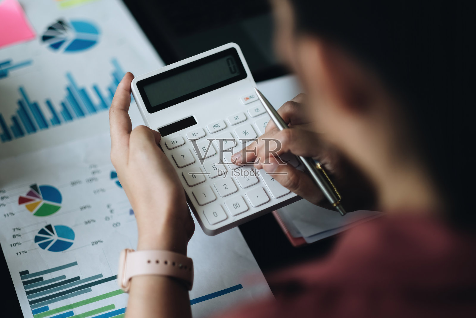 以上的观点，会计女顾问拿着笔，用计算器和财务报告在家里的木桌上。自由职业者，税务，会计，统计和分析研究的概念照片摄影图片