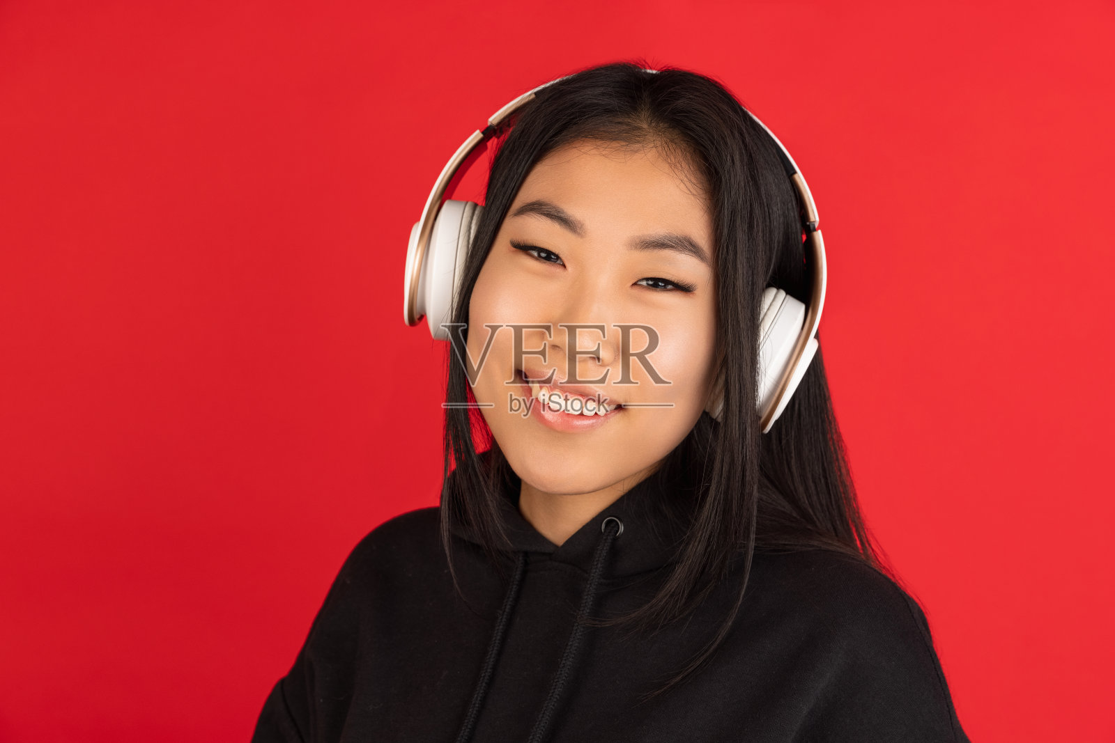 亚洲年轻女孩的肖像孤立在红色工作室背景。照片摄影图片