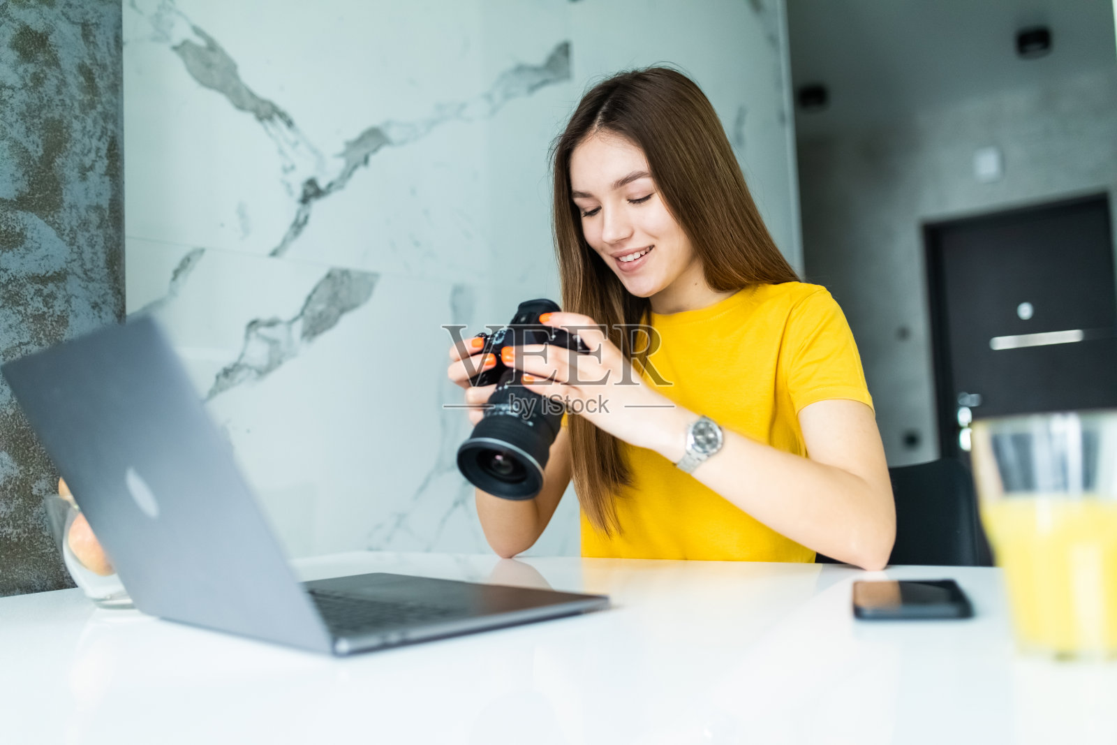 快乐的年轻女性主管看着相机在创意办公室。自由摄影师女性与相机在家办公编辑电脑上的照片照片摄影图片