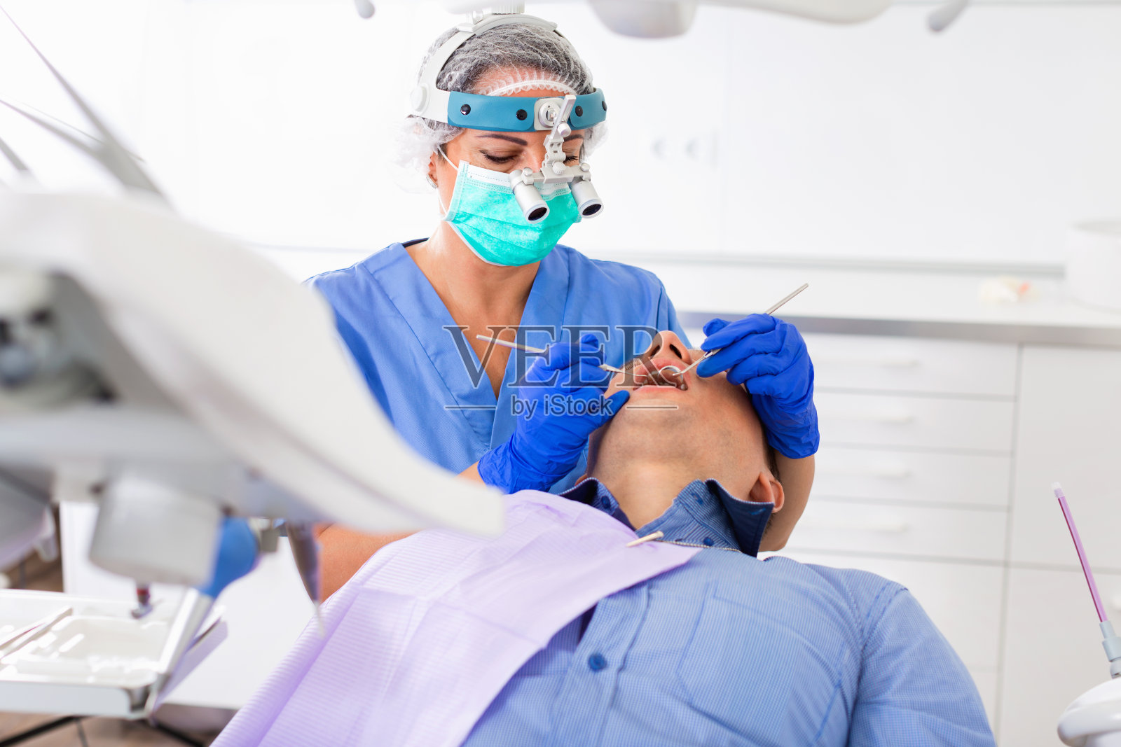 成年牙医在医疗中心检查男性病人的牙齿照片摄影图片