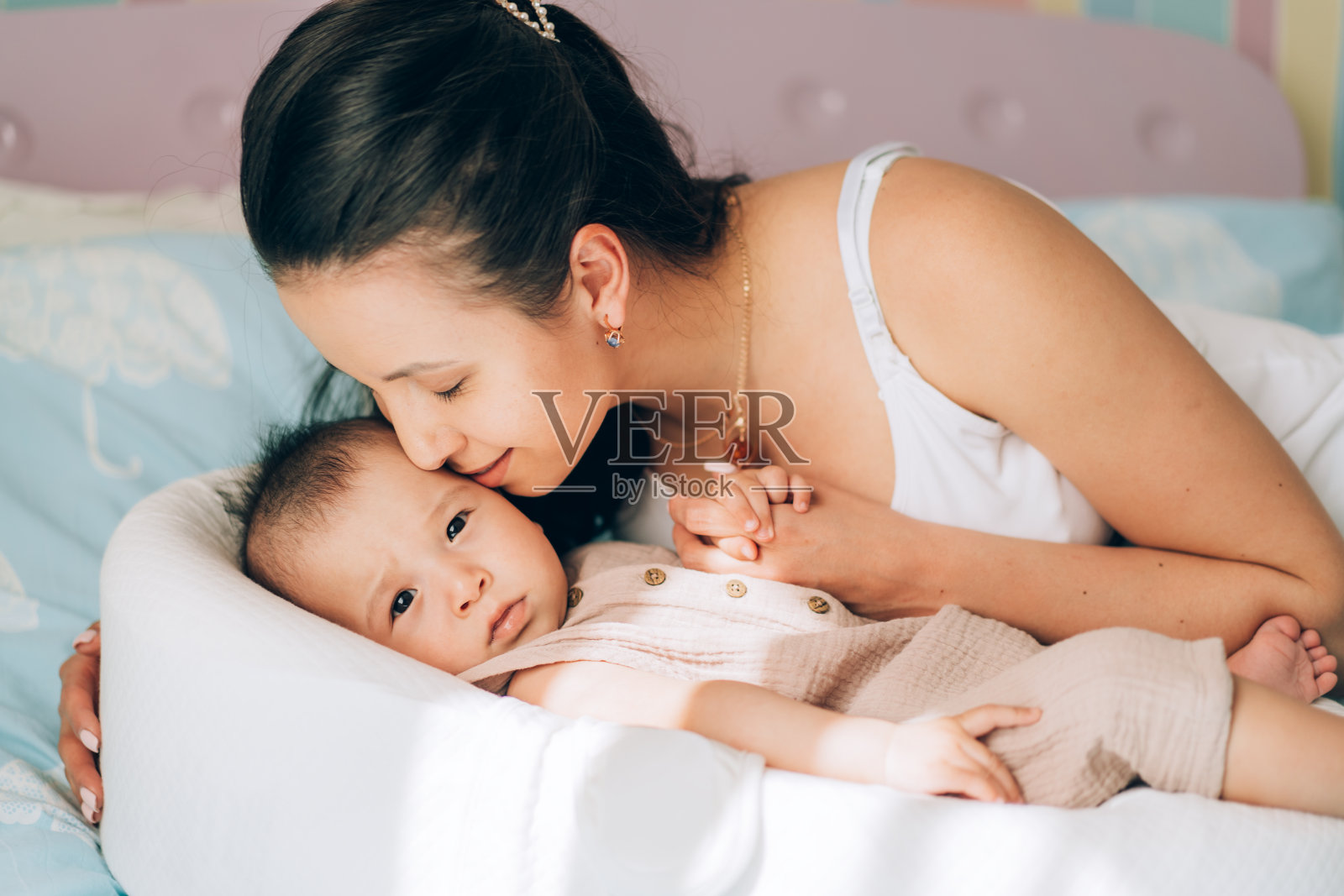 年轻的单身妈妈亲吻她的混血宝宝。儿童领养与体外受精(IVF)。亚洲宝宝和印度妈妈照片摄影图片