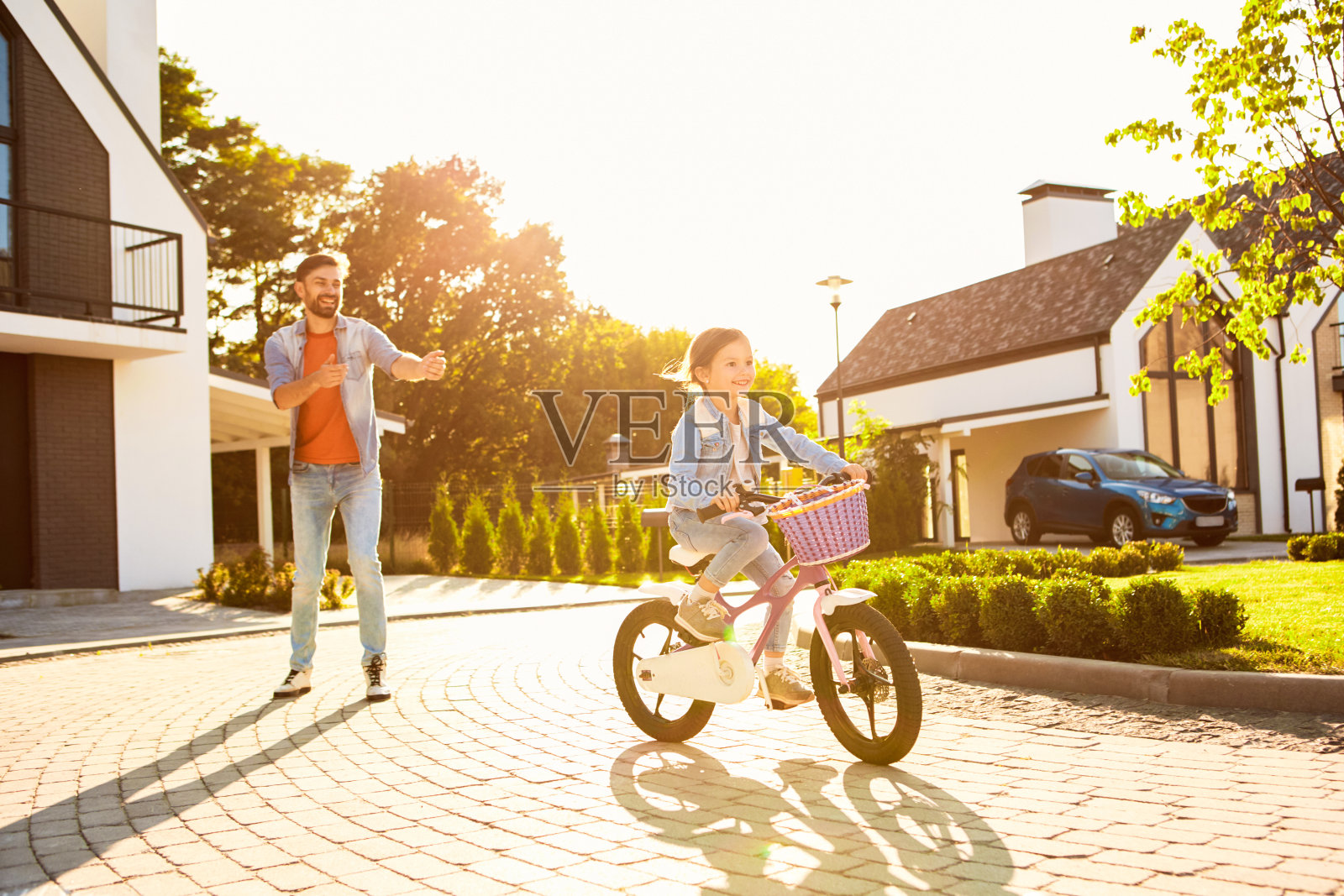 都市村庄。父亲教女儿骑自行车兴奋地在户外附近照片摄影图片