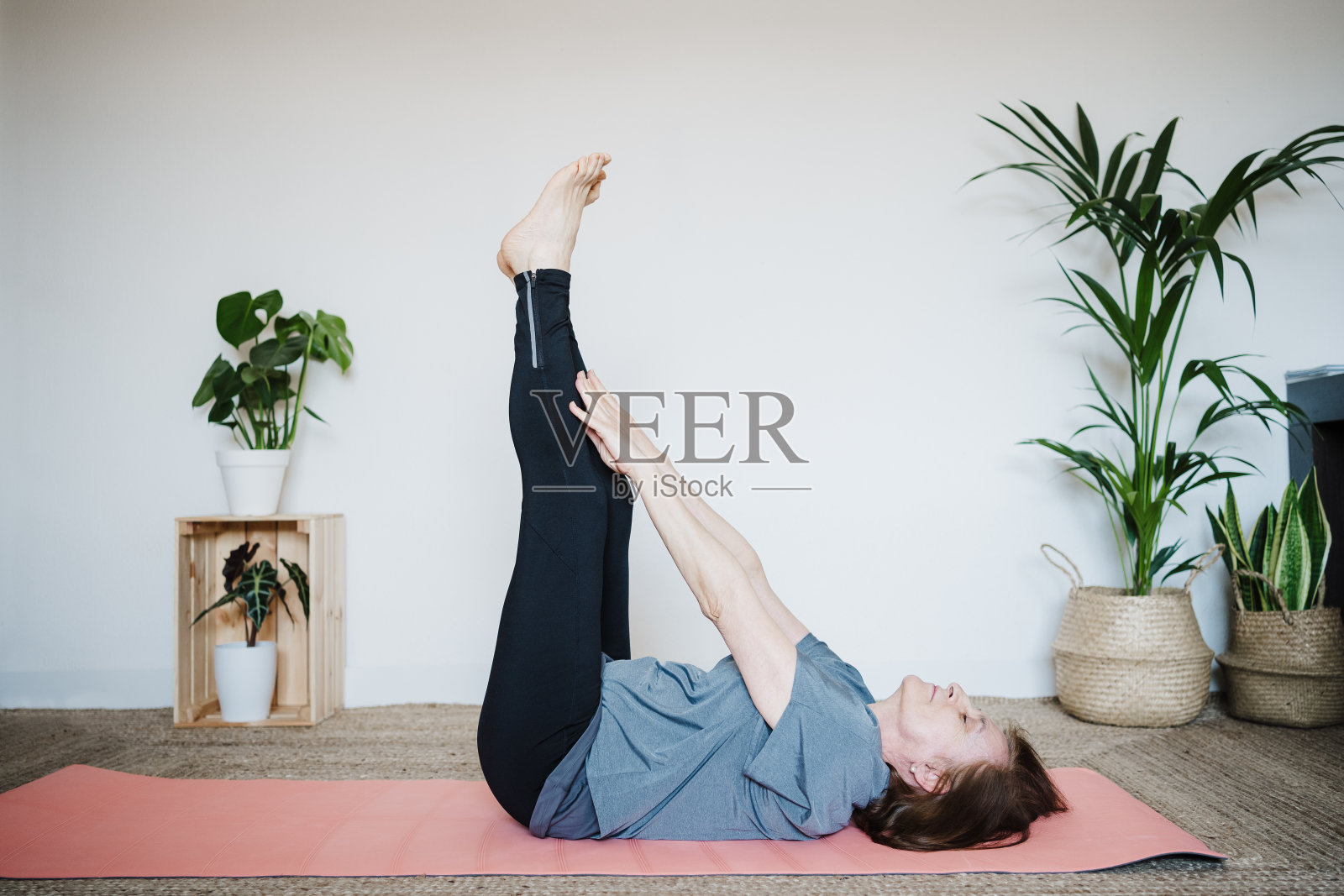 成熟的白人老年妇女在家里练习瑜伽姿势。健康的生活方式照片摄影图片