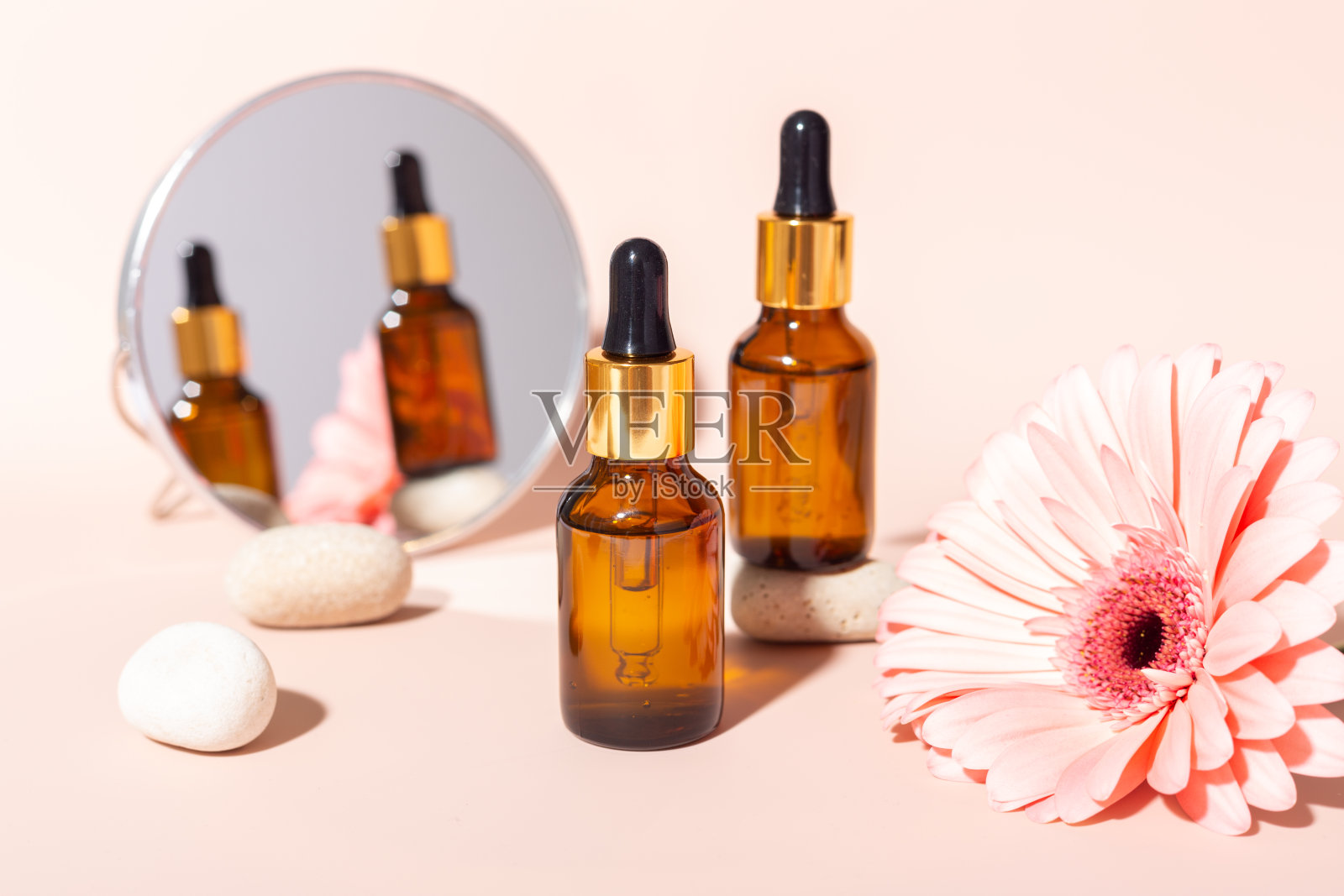 一套面部血清在玻璃瓶与移液管，天然有机水疗化妆品。粉红色的花大丁草。皮肤护理的概念照片摄影图片