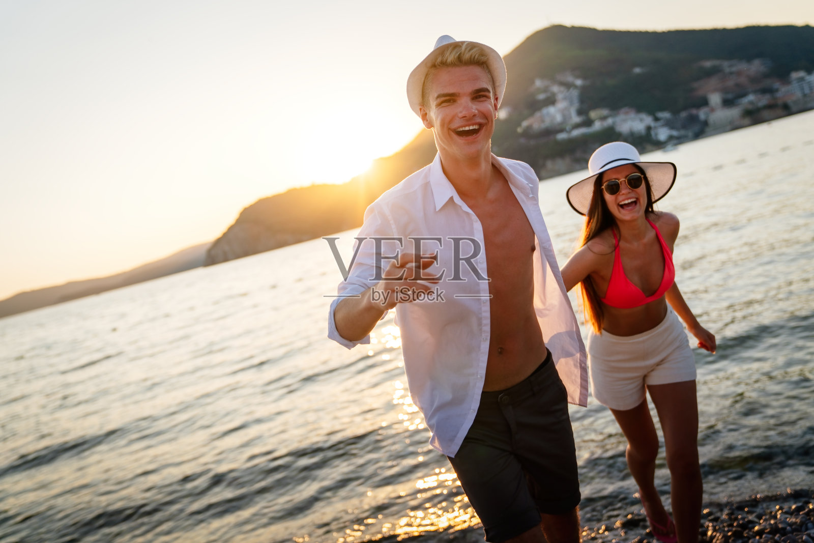 一对迷人的情侣在美丽的海滩上散步，享受暑假照片摄影图片