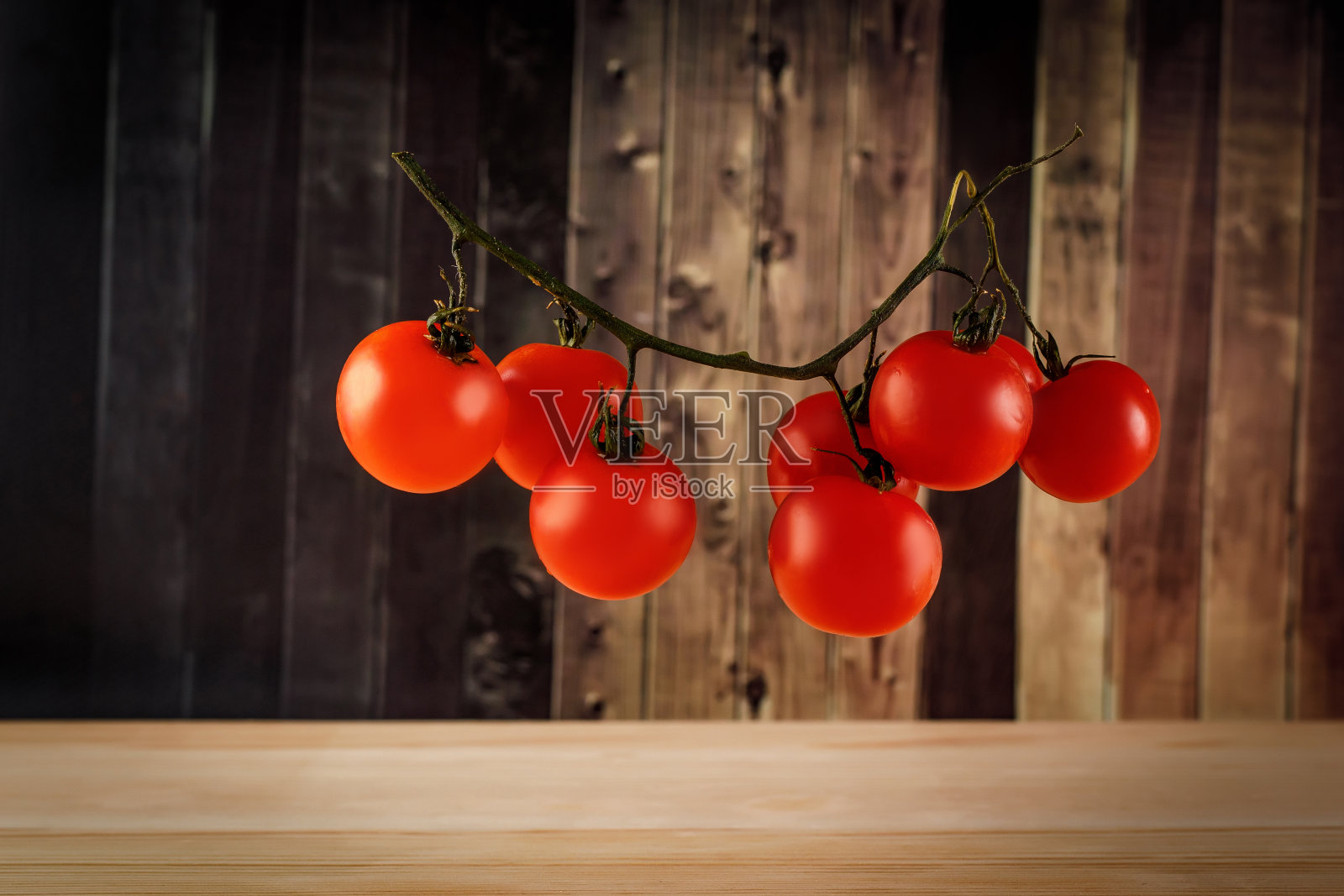 树枝上的樱桃番茄。木制背景。照片摄影图片
