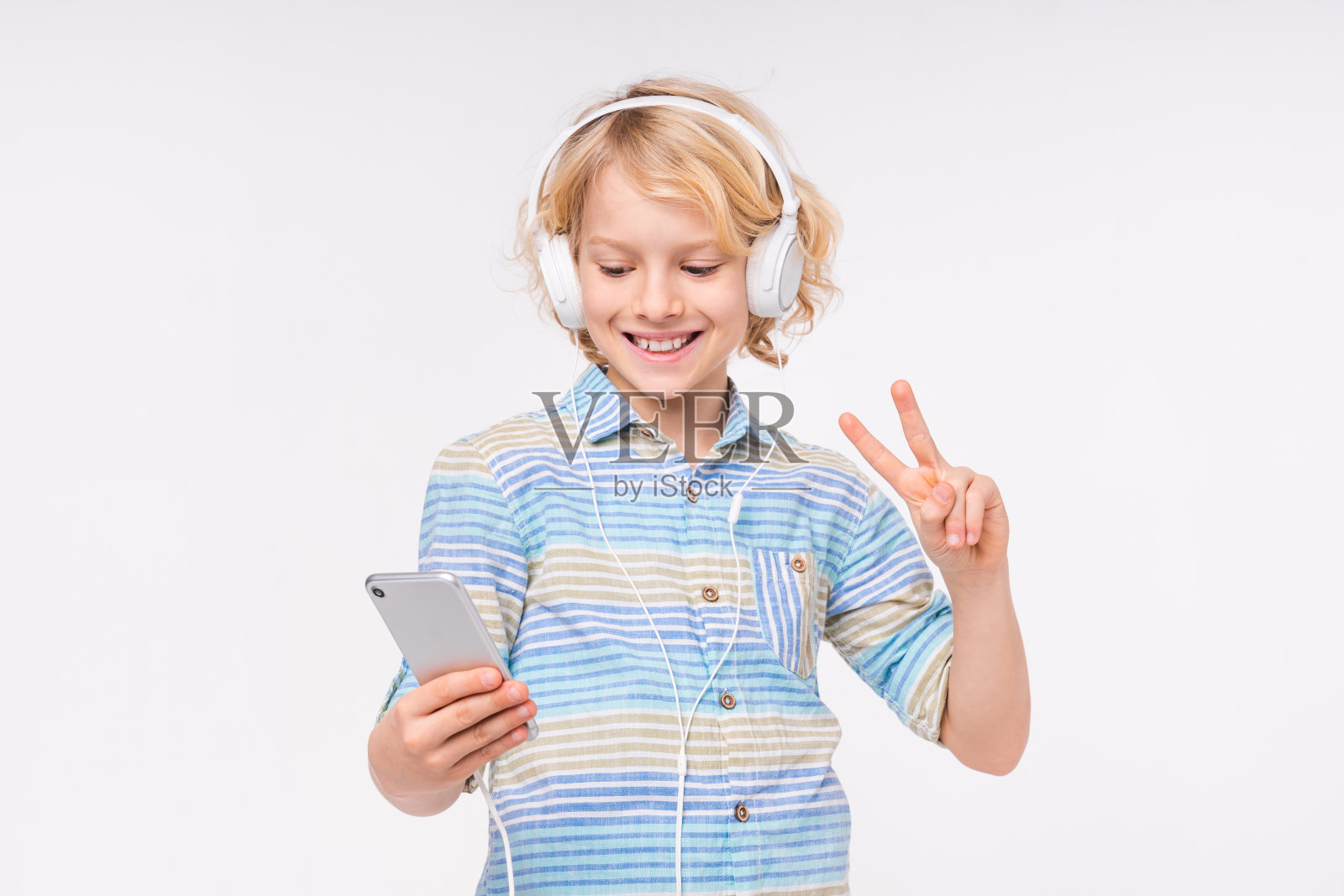 乐观的白人男孩在白色背景上戴着耳机自拍照片摄影图片