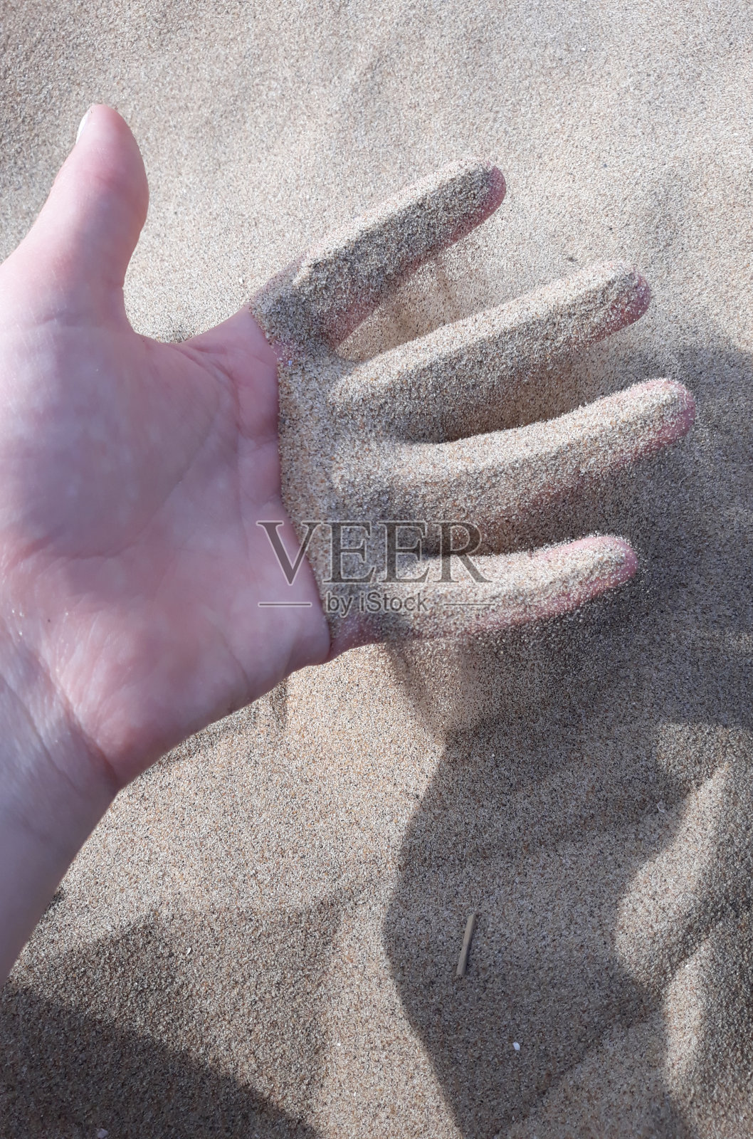 在荷兰海滩逗留期间，孩子手指上的沙滩沙子照片摄影图片