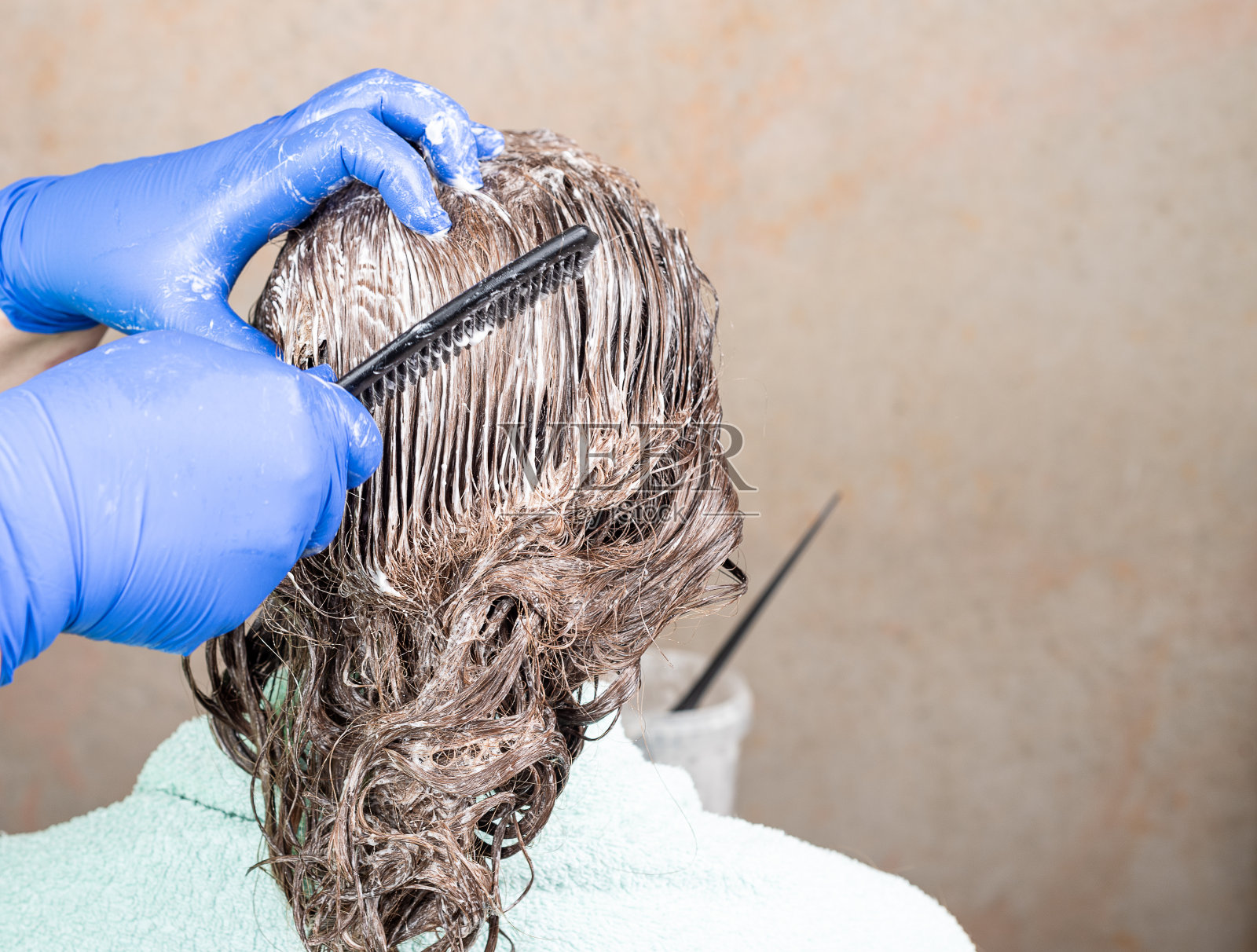 用梳子在女性头发上涂抹颜料。照片摄影图片