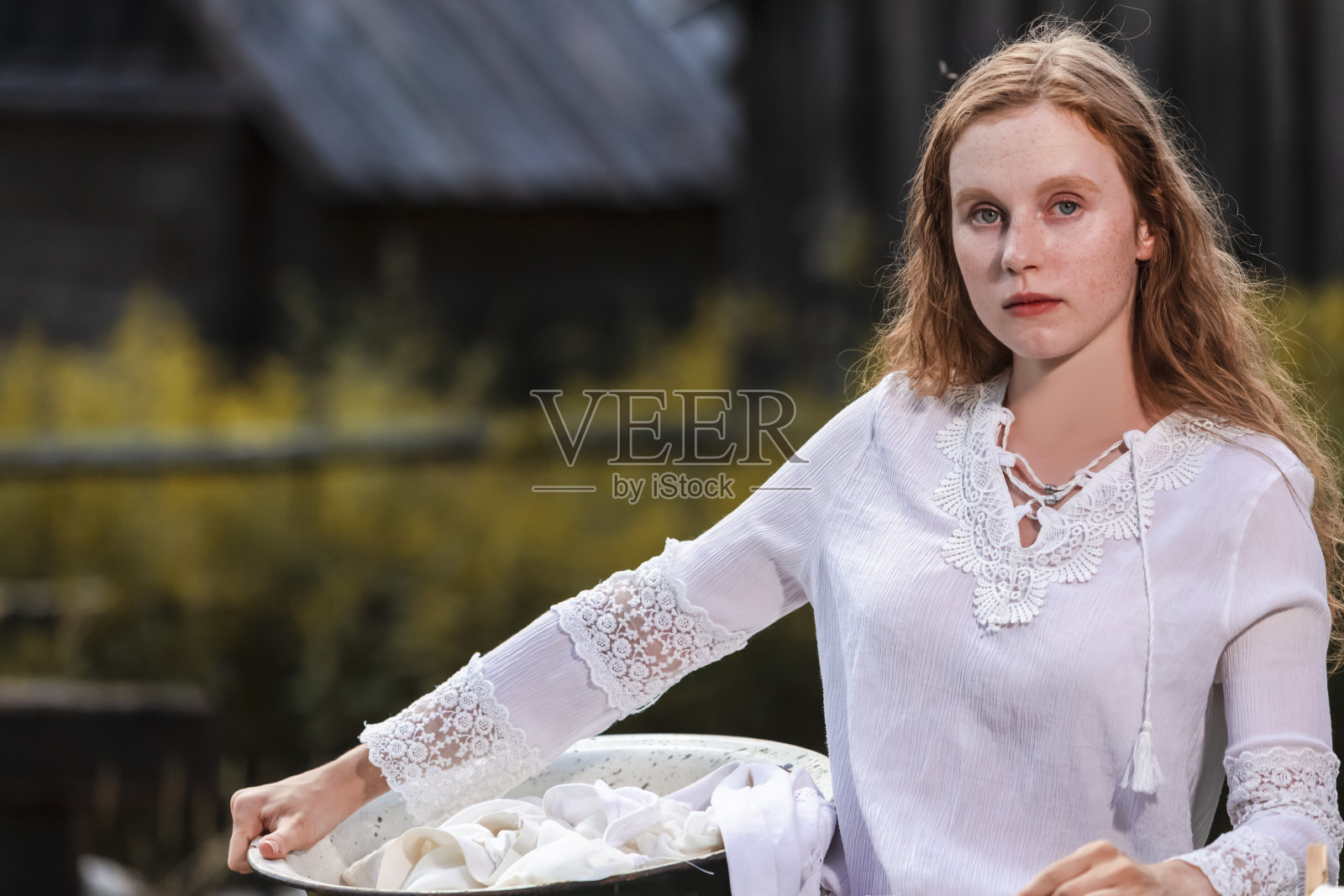 冷静的红发白人女孩的自然肖像与洗衣盆在一个乡村环境。水平方向照片摄影图片