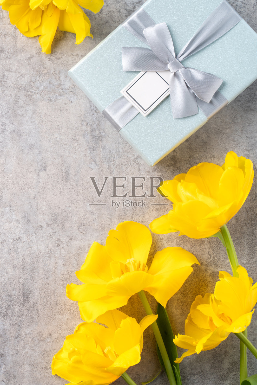 母亲节的背景。顶视图的礼物与黄色郁金香花束在灰色的桌子背景照片摄影图片