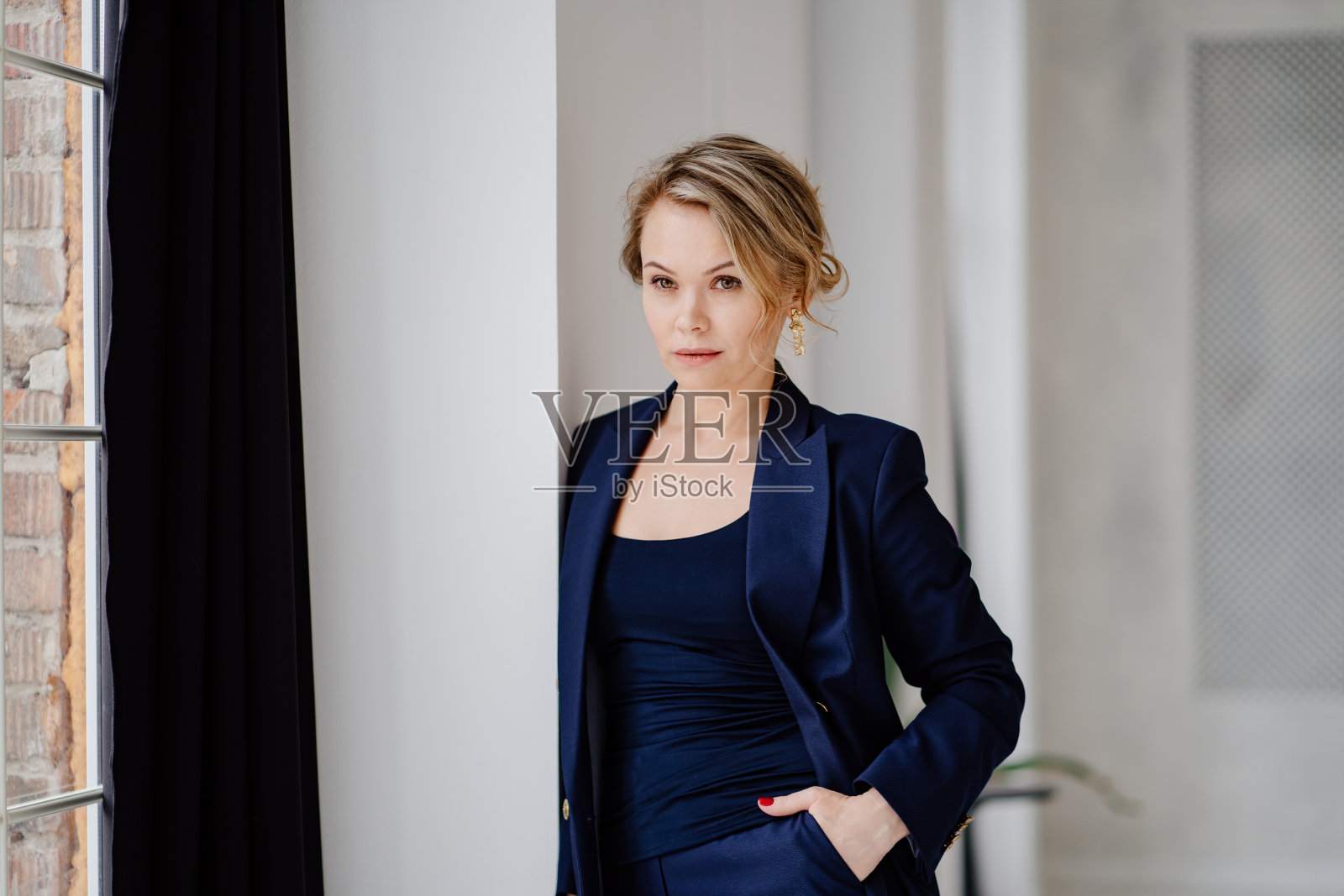 一个身穿蓝色西装的金发女人站在照相馆里。女商人照片摄影图片