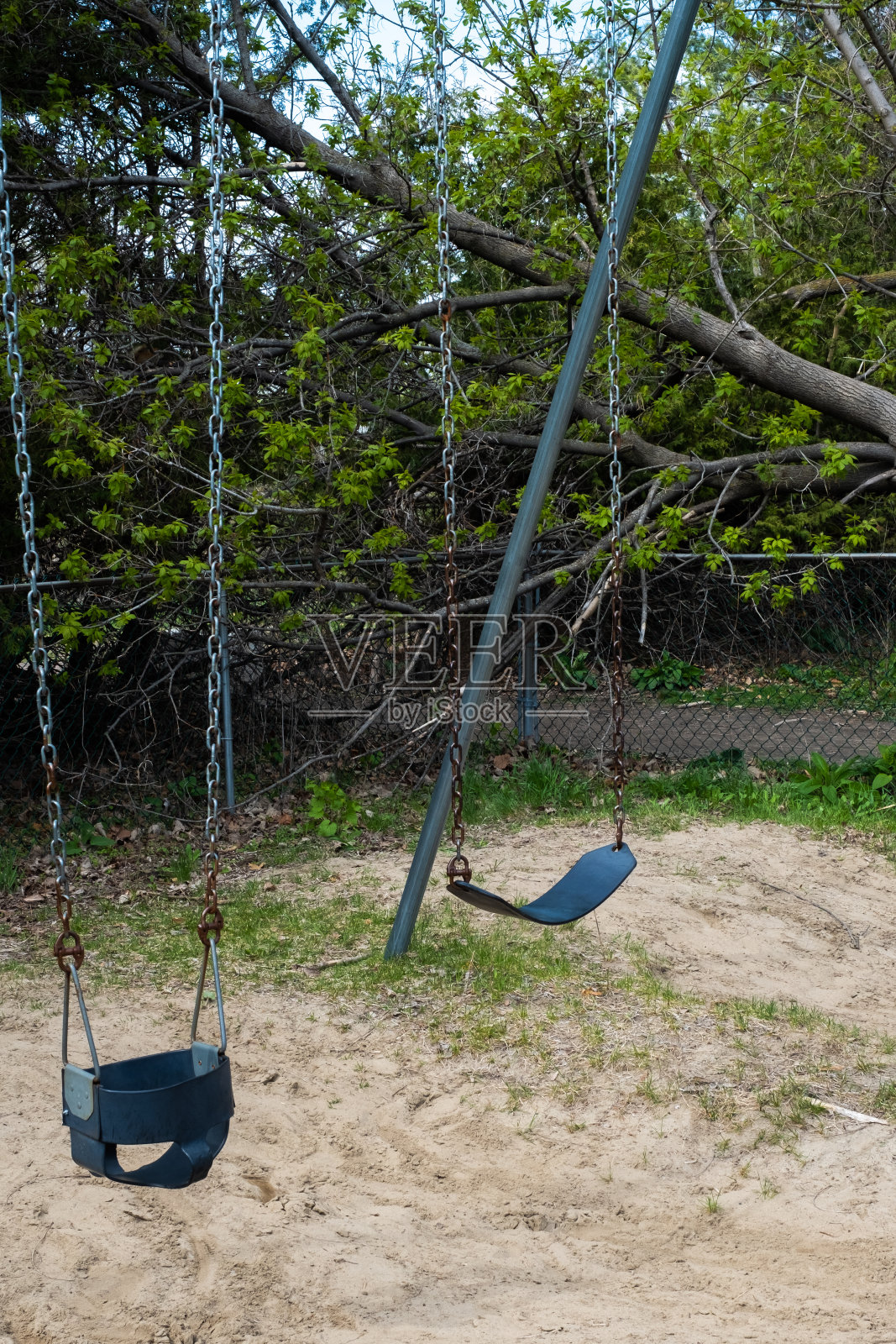空秋千组，周围有铁链围栏照片摄影图片