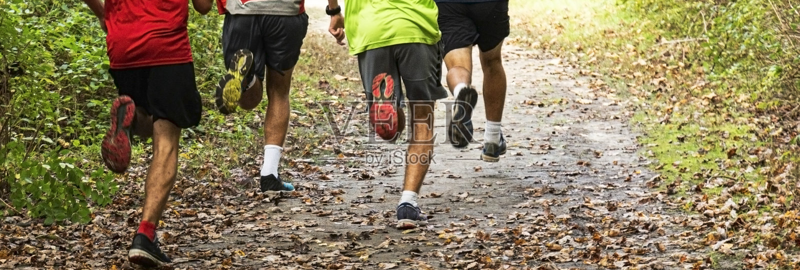 在公园里，男孩们在一条满是树叶的土路上奔跑照片摄影图片
