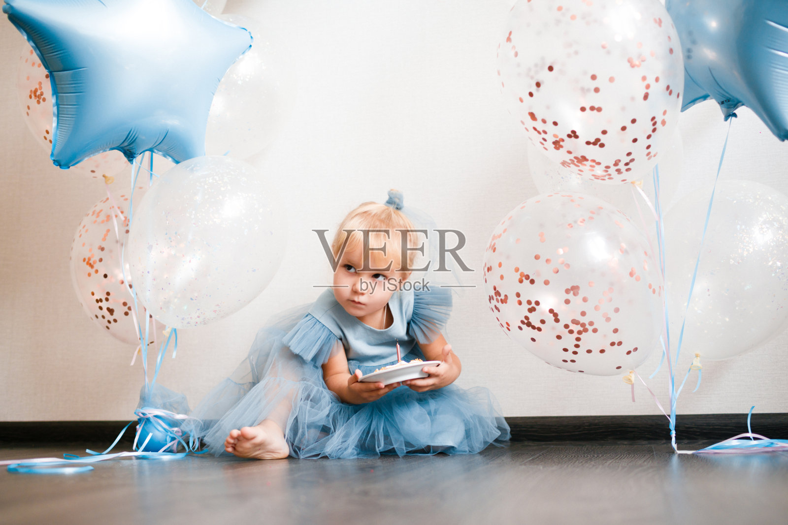 金发小女孩吹灭生日蛋糕上的蜡烛。照片摄影图片