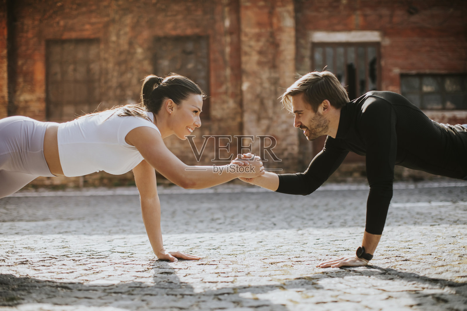 年轻夫妇在城市环境中进行单臂俯卧撑锻炼照片摄影图片