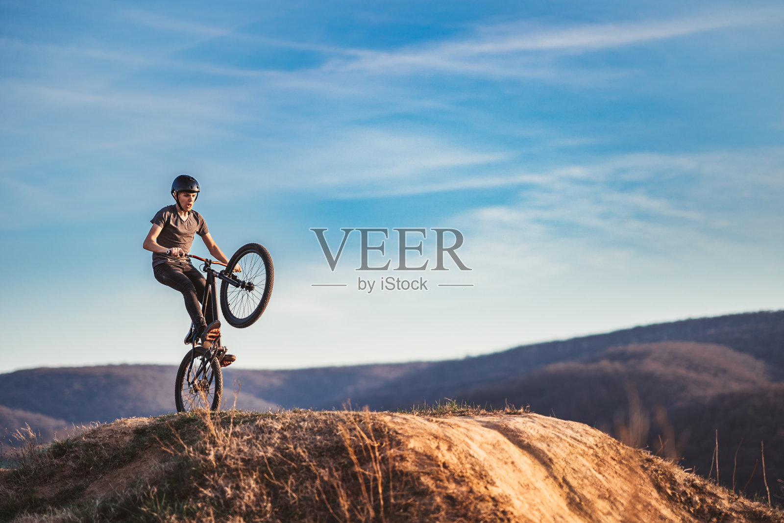 年轻人在山地车上表演土路跳跃照片摄影图片