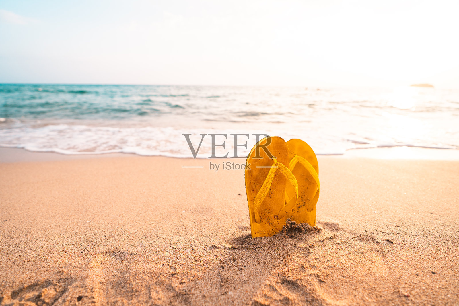 黄色的人字拖在沙滩上照片摄影图片
