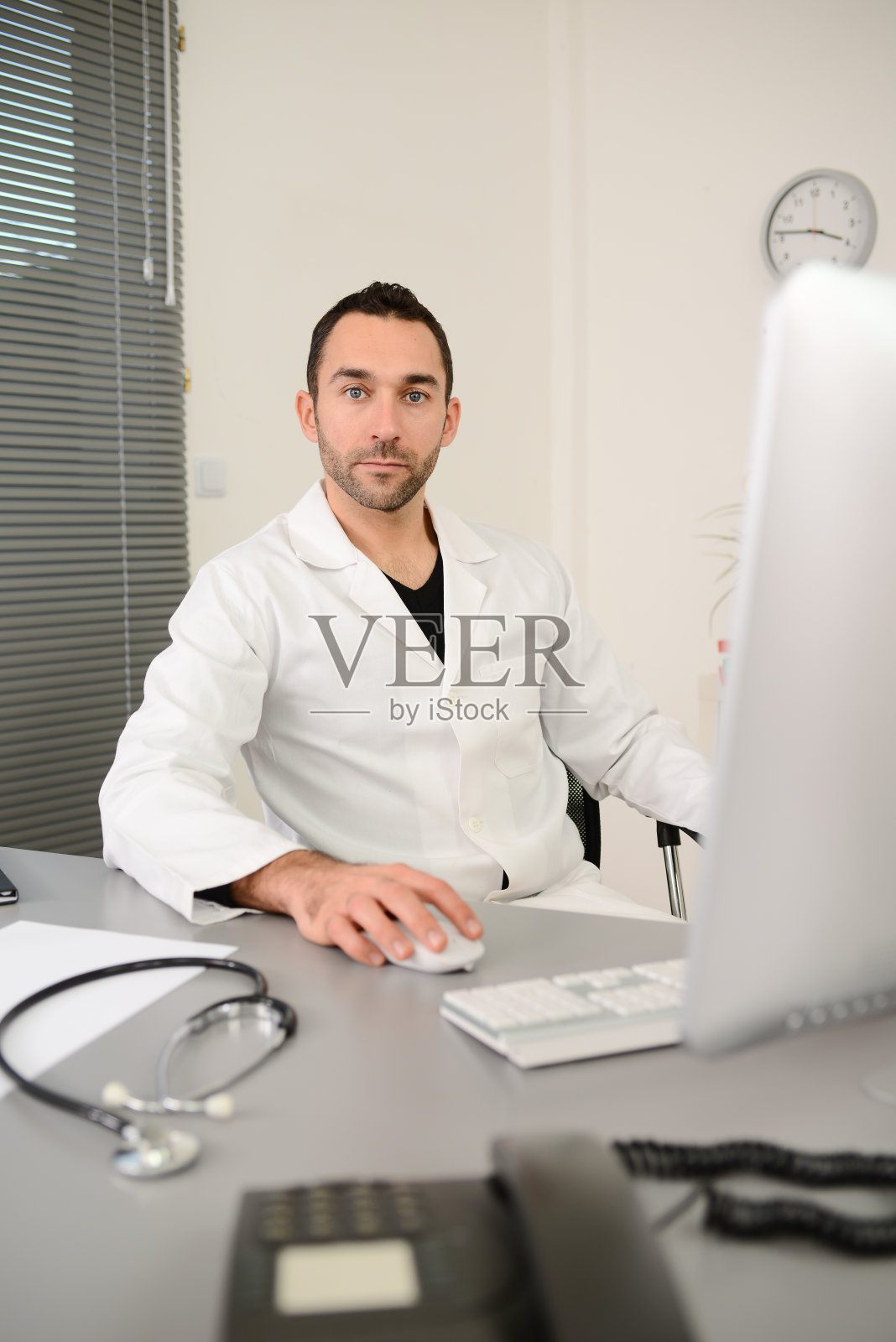 一个英俊的男人男医生在一个医疗实践办公室在电脑上工作的肖像照片摄影图片