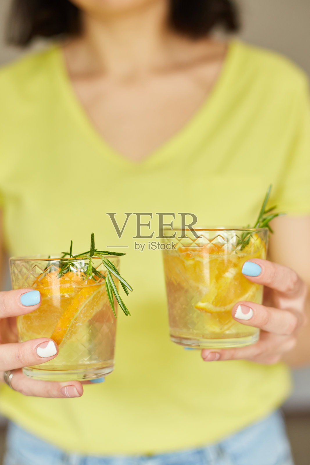 女人手里握着两杯柑橘橙和迷迭香的新鲜柠檬水照片摄影图片