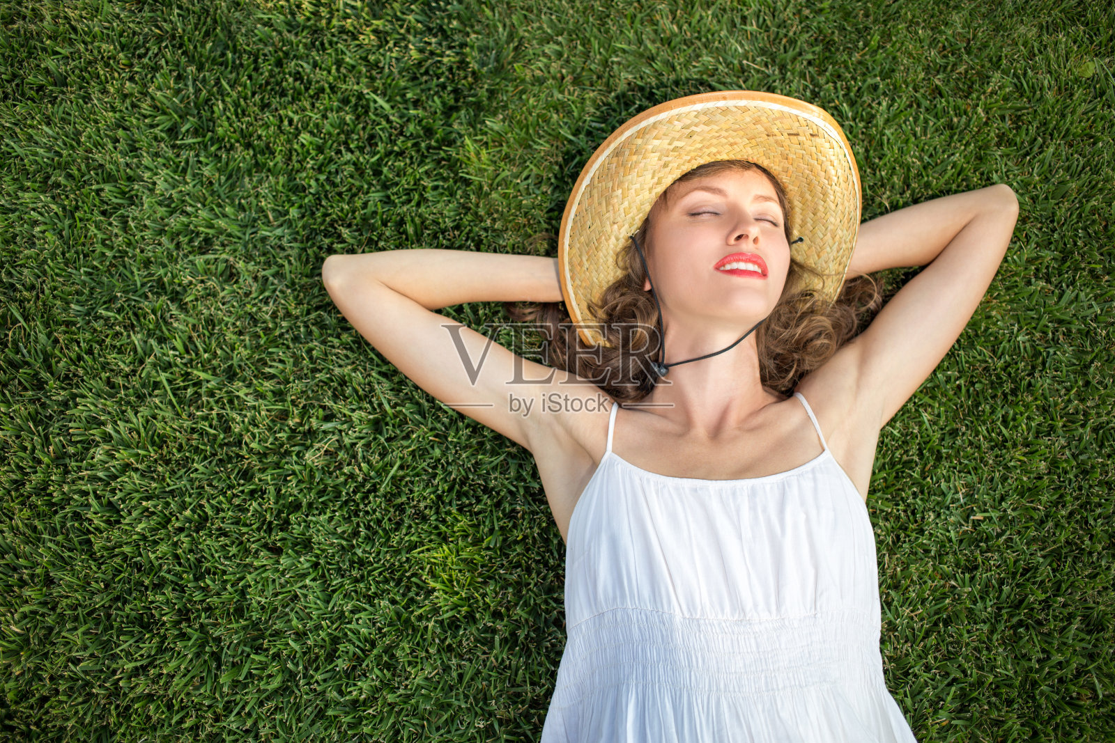 戴着帽子的女人躺在绿色的草地上照片摄影图片