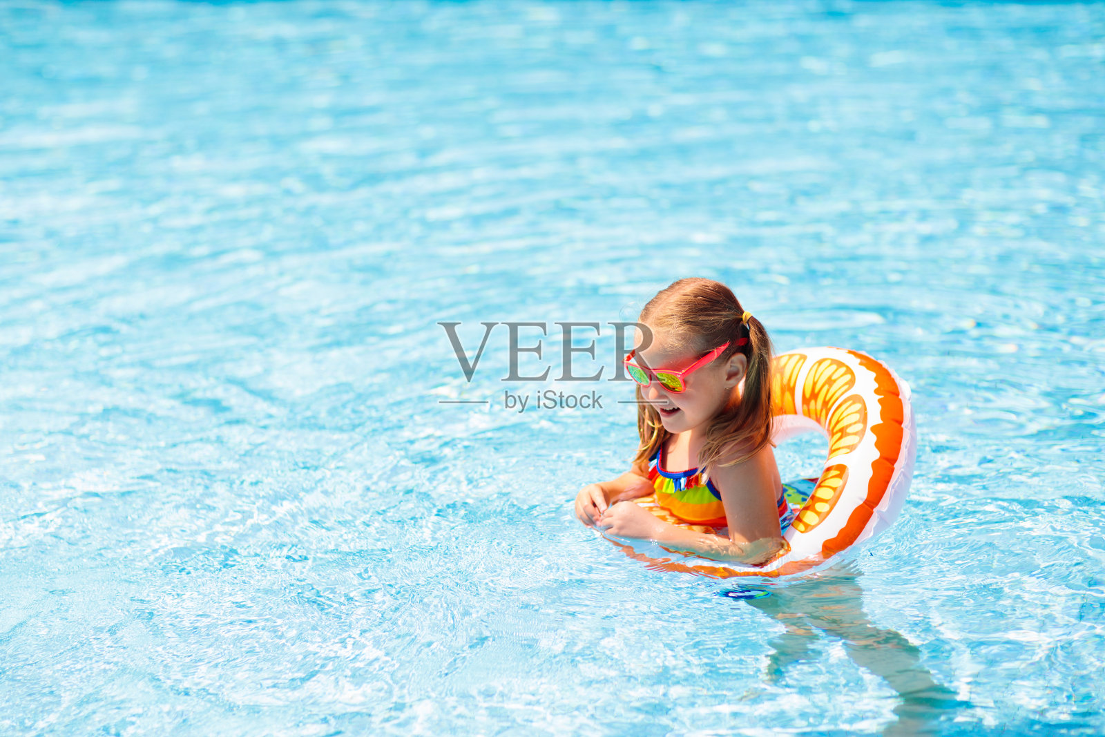 孩子在游泳池里的玩具圈上。孩子们游泳。照片摄影图片