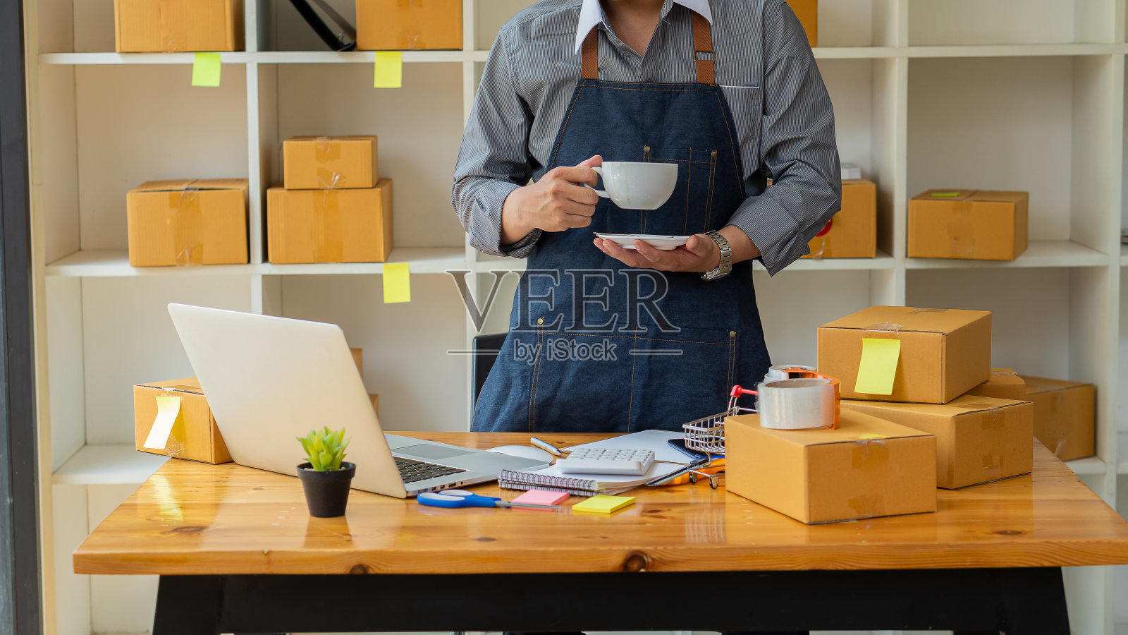 小企业主在工作中使用笔记本电脑和电话，移动和纸板箱，小企业主，中小企业在家里使用盒子，在网上销售，电子商务。照片摄影图片