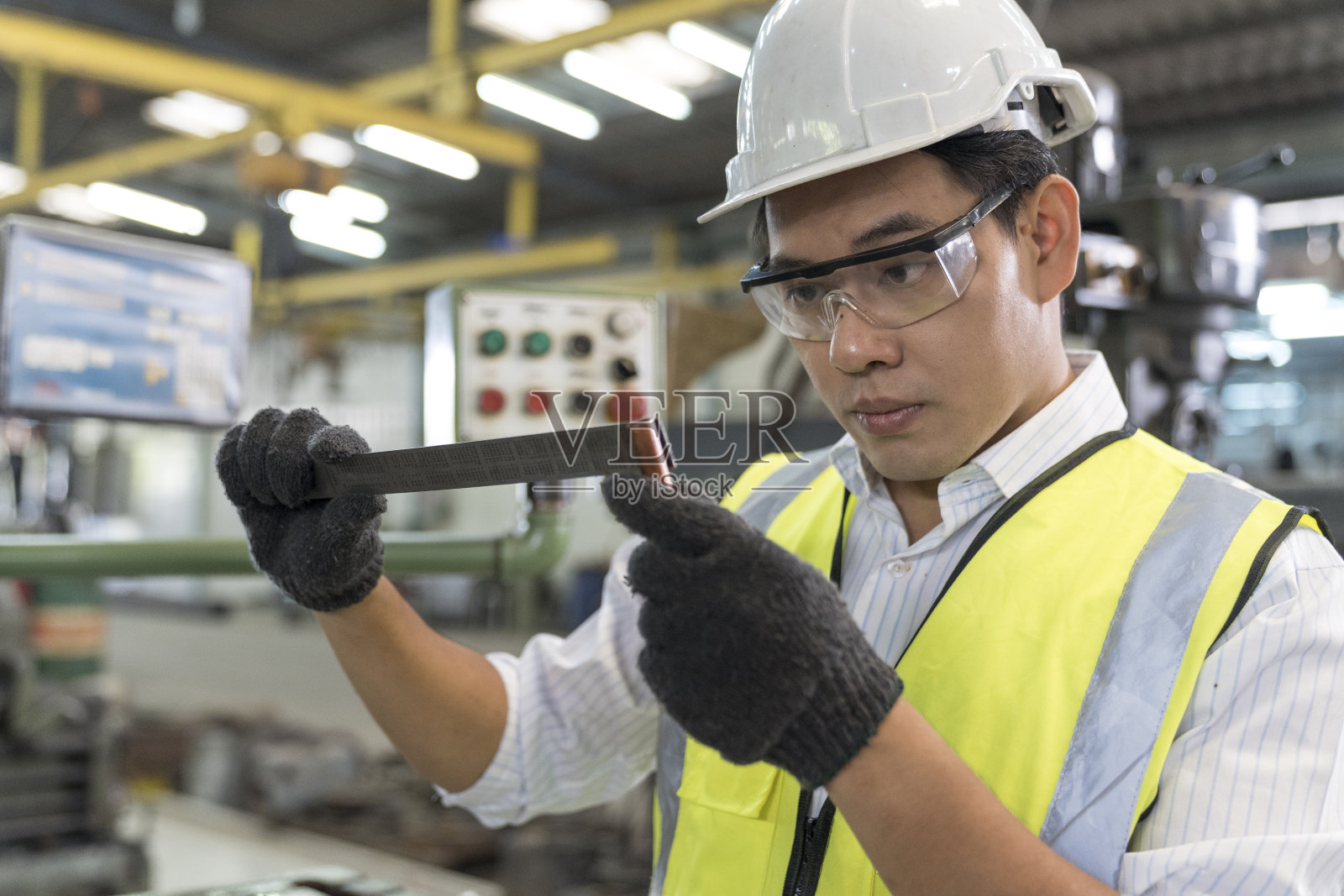 工程师在工业中工作和修理机器。拿着测量钳的技术员。金属游标卡尺测量。照片摄影图片