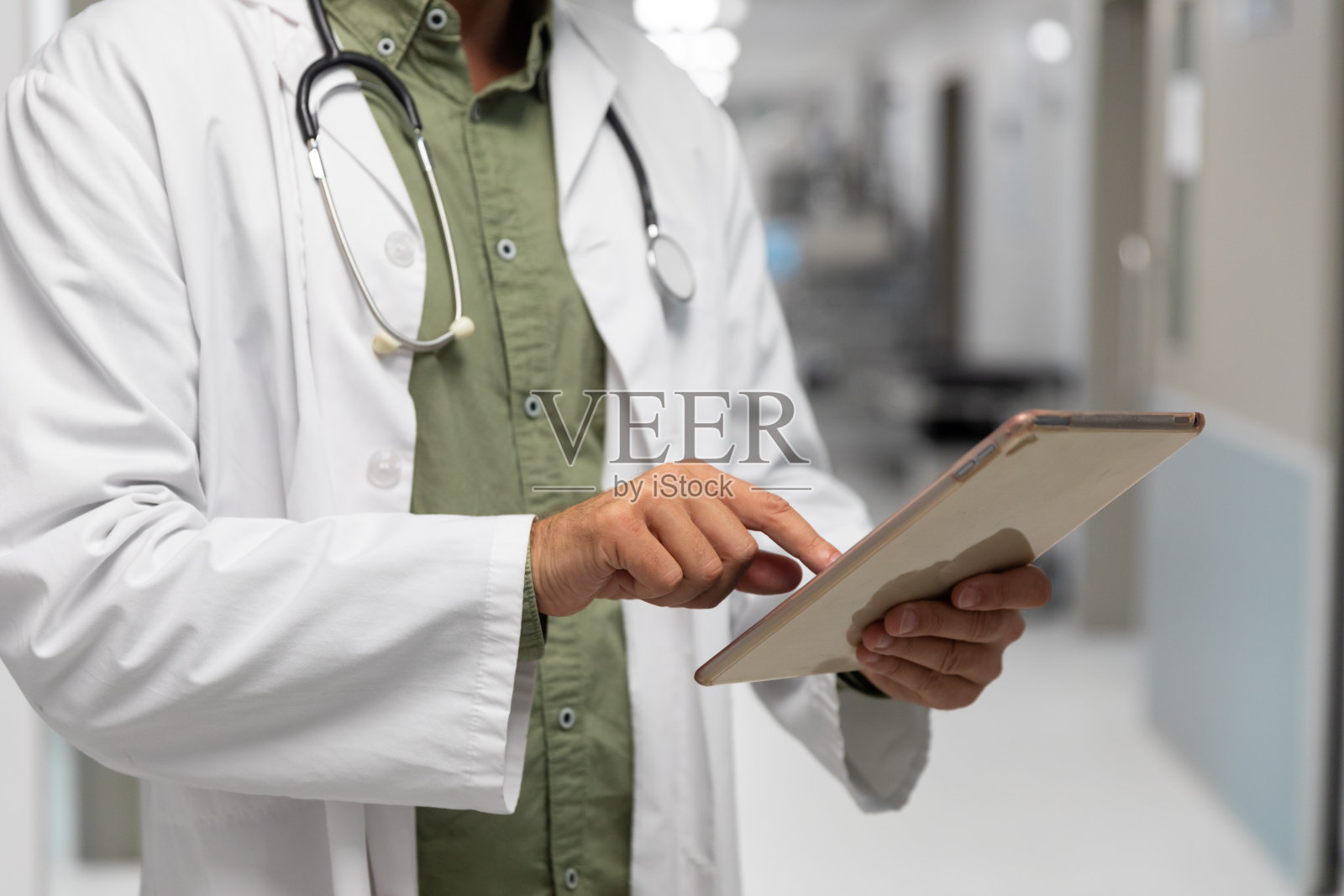 白种男医生站在医院走廊上看片剂照片摄影图片