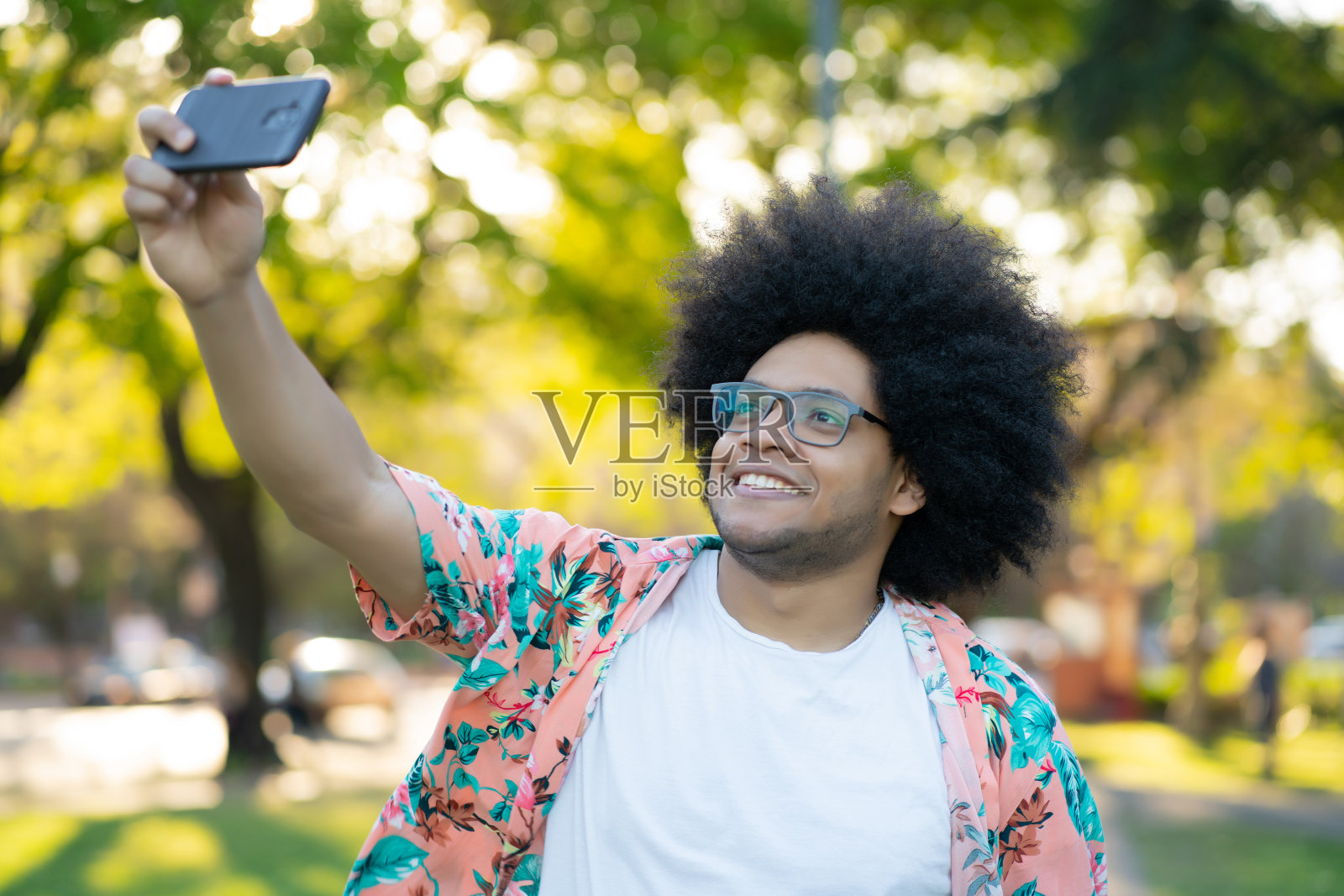一个拉丁男人在户外用手机自拍。照片摄影图片