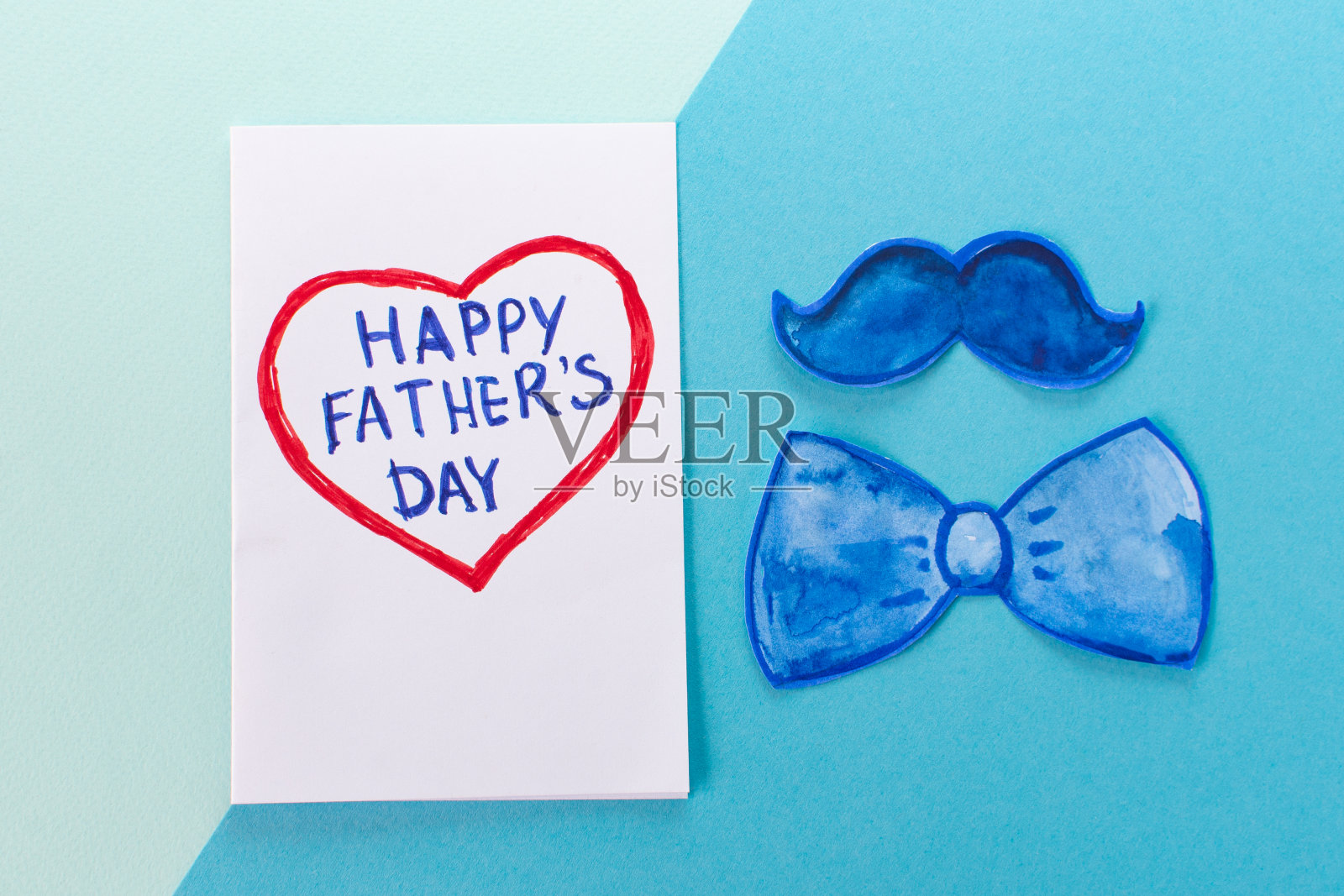 父亲一天的概念。Flatlay。滑稽的小胡子，蝴蝶结和心形卡片，上面写着:以最小的蓝色为背景，父亲节快乐照片摄影图片