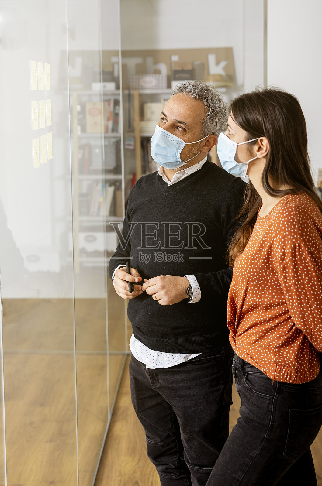 同事们在办公室用玻璃板讨论想法照片摄影图片