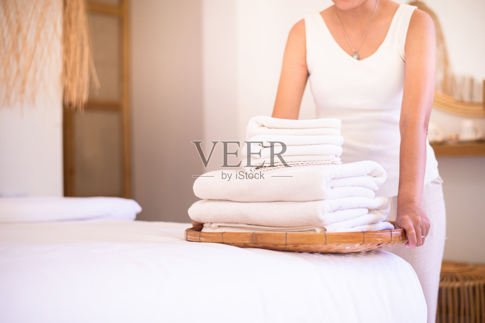 酒店女服务员把干净毛巾叠在床上，颜色是白色的照片摄影图片